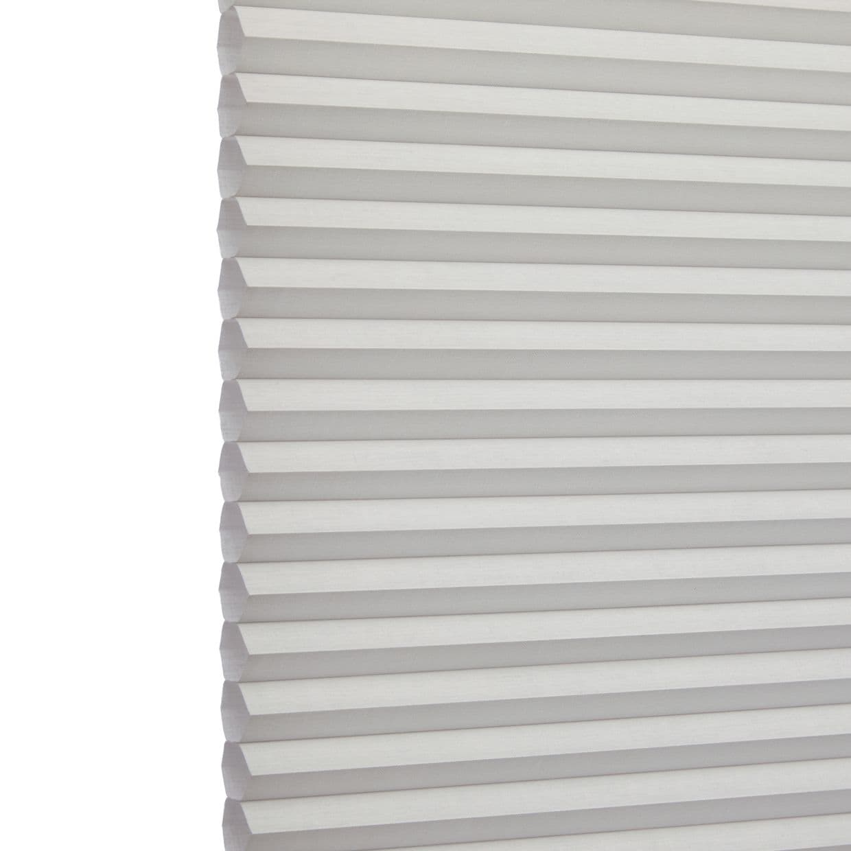 White cellular (honeycomb) blind, left-edge visible with uniform horizontal pleats; fully lowered and closed, softly filtering daylight; set against a bright, neutral interior background.