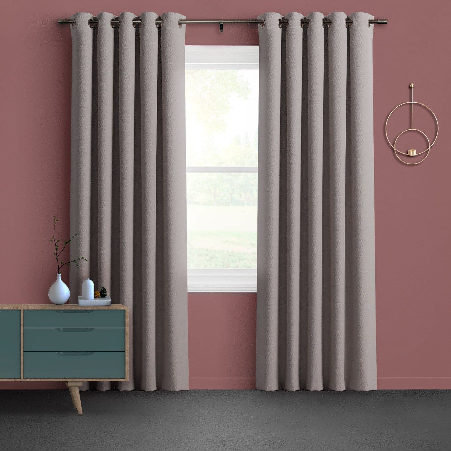 Grommet-top beige floor-length curtains, hung in even folds on a metal rod and partially open, filtering soft daylight through a white-trim window in a muted-rose living room.