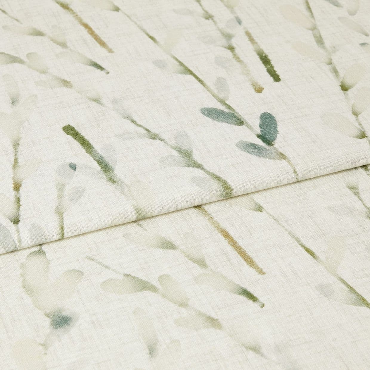 Light, folded curtain fabric with watercolor green leaf sprigs, draping in a horizontal fold; filtering soft light, photographed close-up to show linen texture and subtle botanical print.