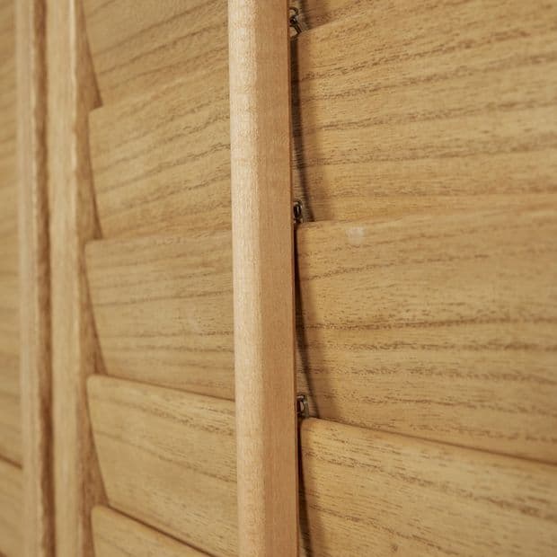 Wooden louvered shutters with vertical stile and narrow horizontal slats, tightly closed; close-up interior view showing warm, grainy oak texture and soft ambient light.