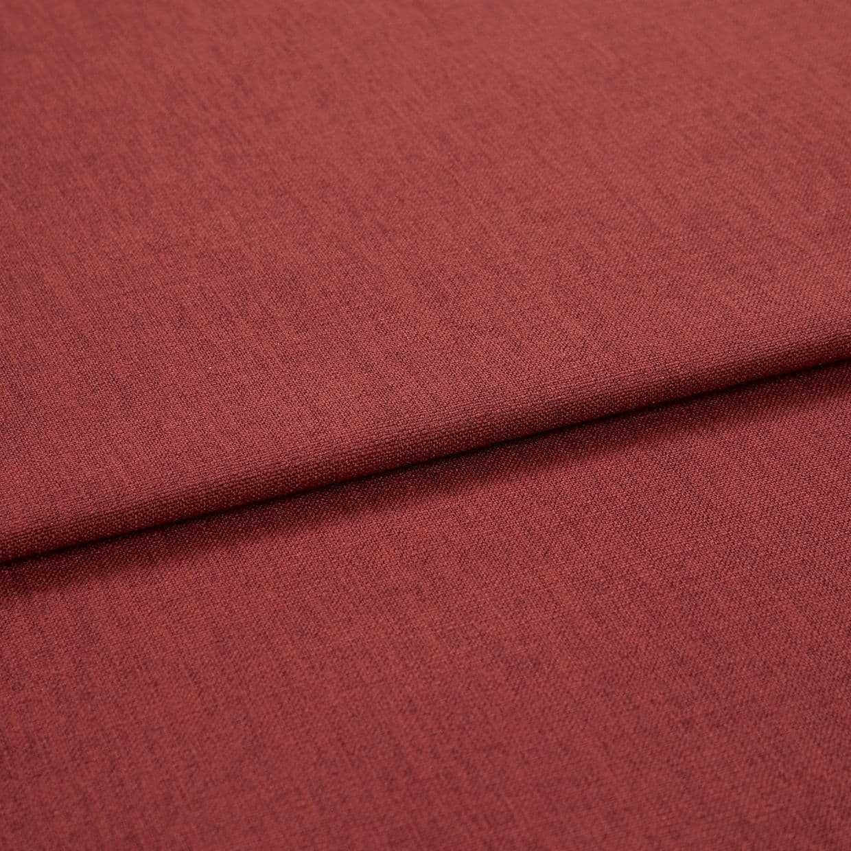 A folded red-brown woven upholstery fabric, folded once across the frame; fine, even weave visible, shown in close-up with soft, even studio lighting.