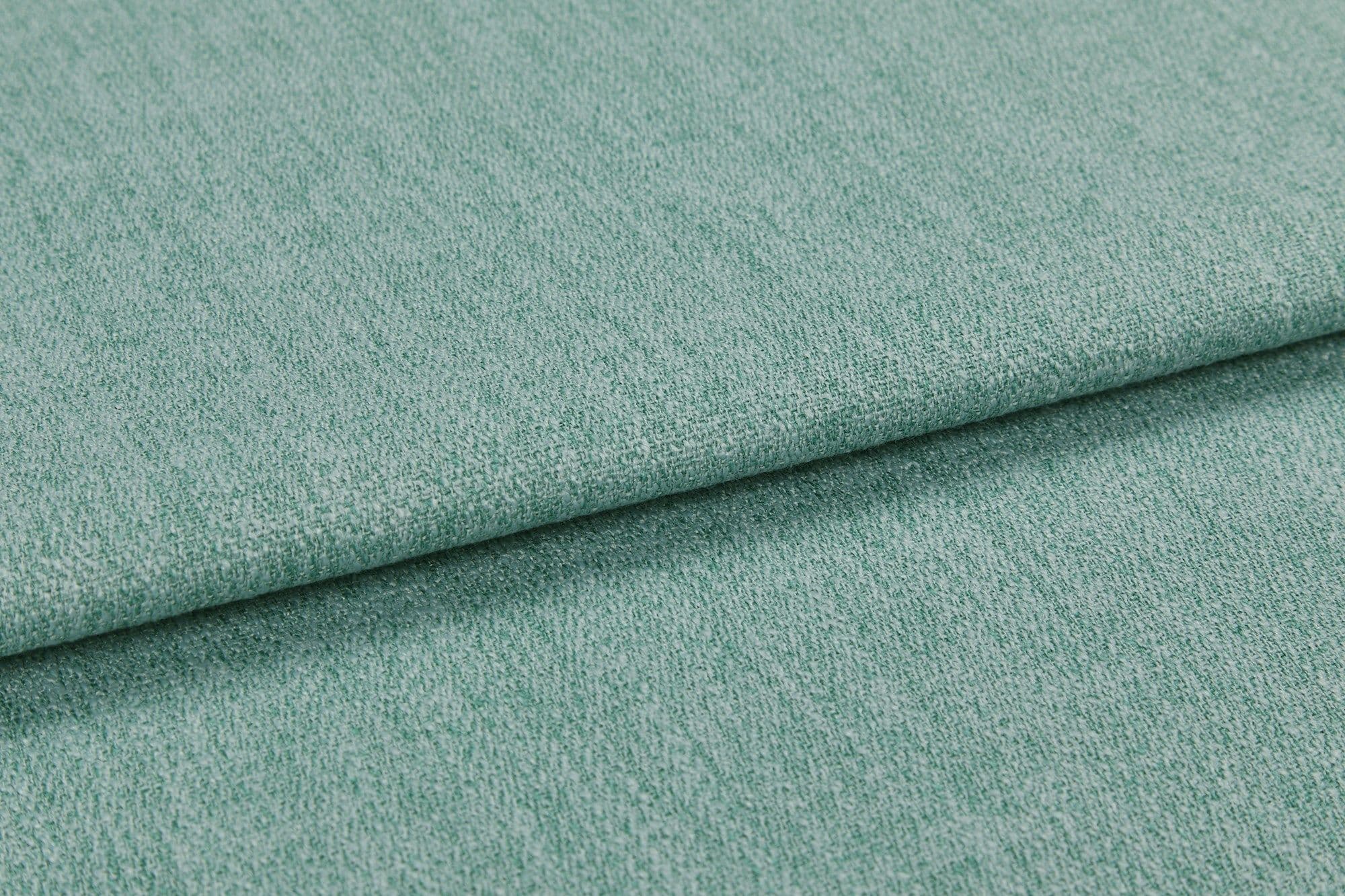 A folded teal-green textured upholstery fabric, layered with a visible fold across the frame; close-up view showing woven pile under soft, even studio lighting.