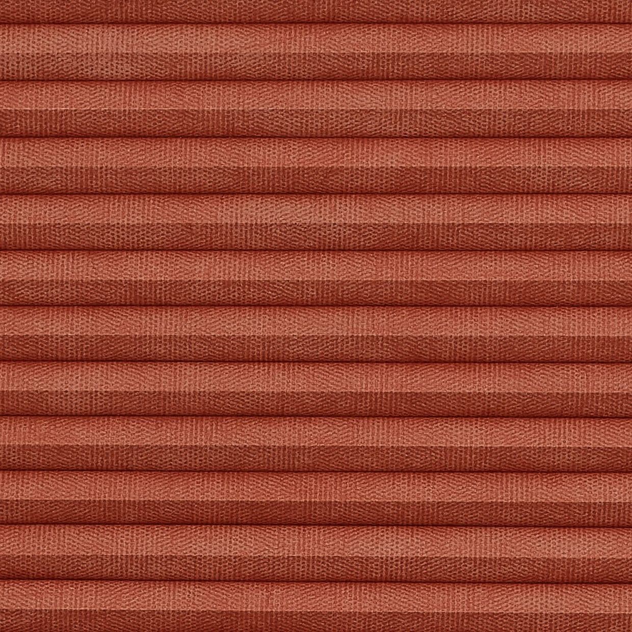 Pleated cellular blind, tightly closed, terracotta textured fabric with horizontal ribs; blocking view and softly diffusing light, close-up framing fills the frame with warm, even illumination.
