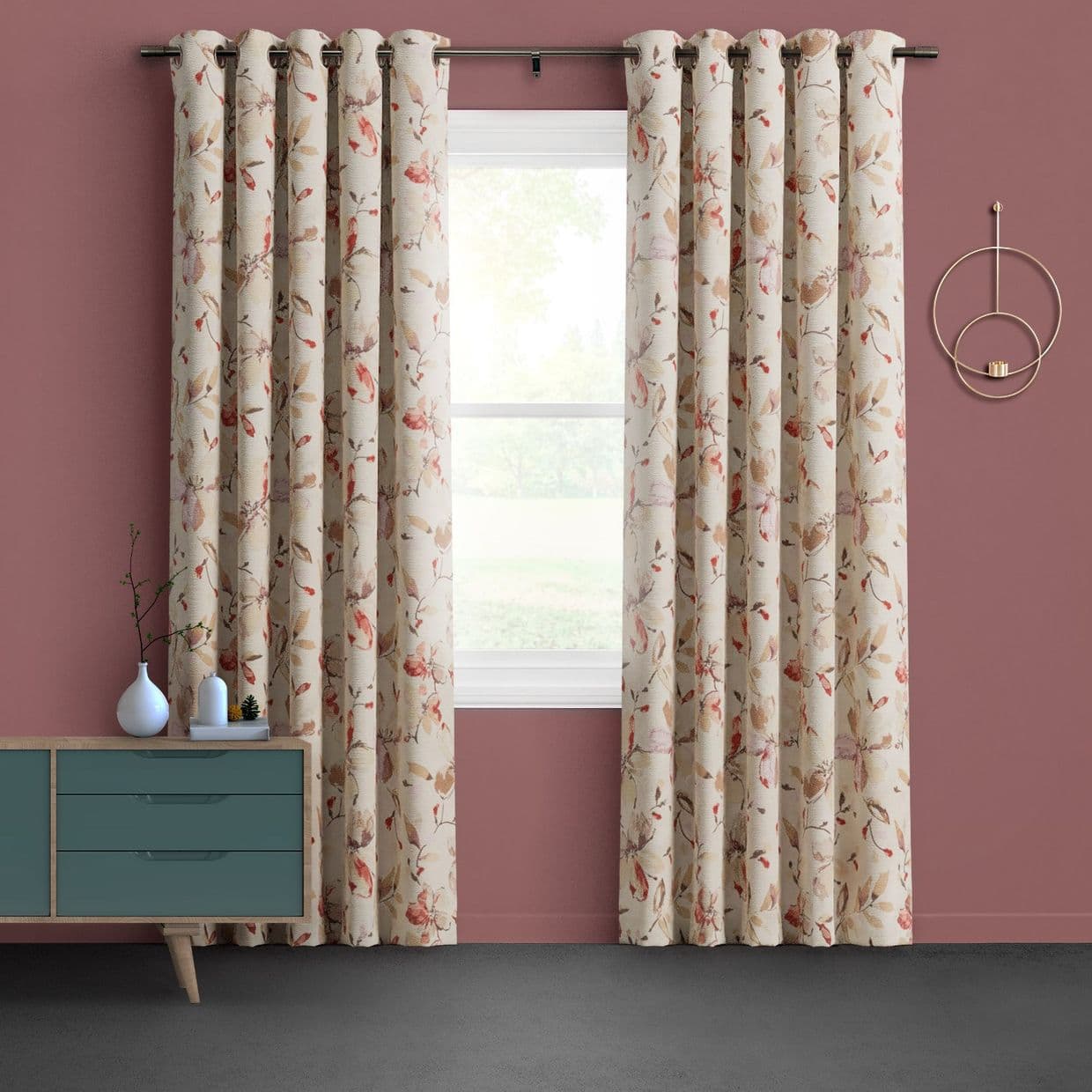 Floral grommet curtains (cream with pinkâ€‘beige leaves) hang on a rod, parted to frame a window; set against mauve walls with a teal dresser and circular sconce, lawn visible outside.