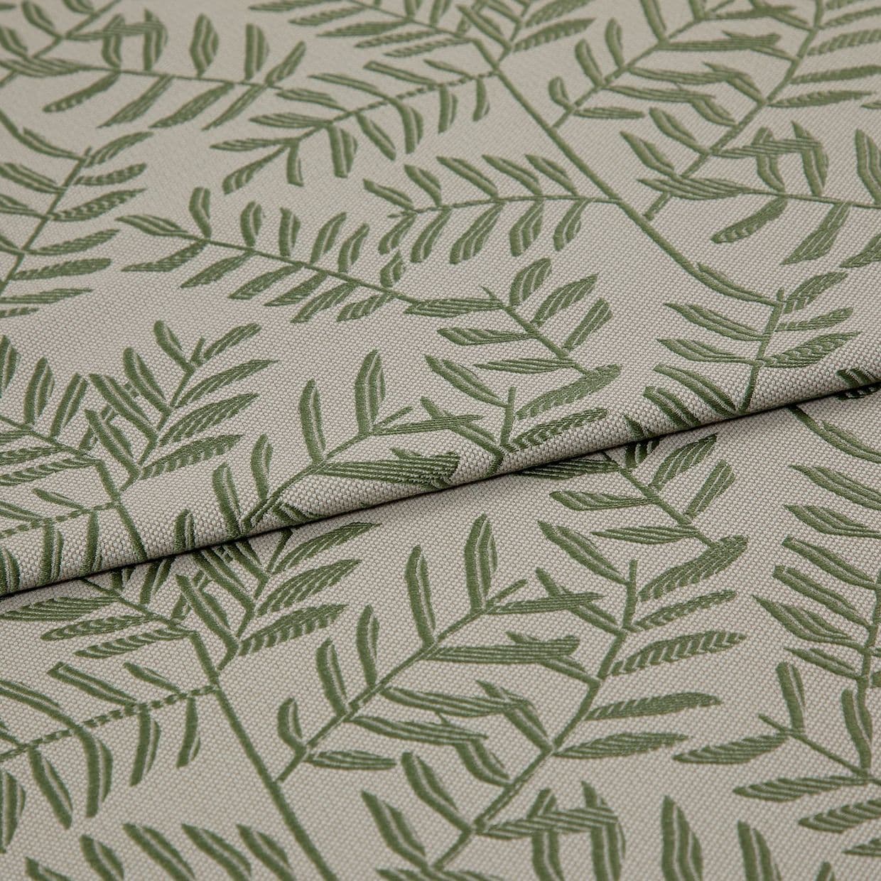 Beige woven fabric panel printed with green fern-like branches (textured weave) â€” lying with two overlapping folds â€” close-up on a neutral surface under soft, even lighting.