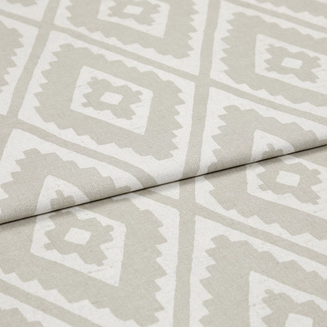 Folded woven upholstery fabric with beige-and-white diamond Aztec-style pattern, folded diagonally across the frame; crisp texture visible, photographed in soft, even studio lighting as a close-up.