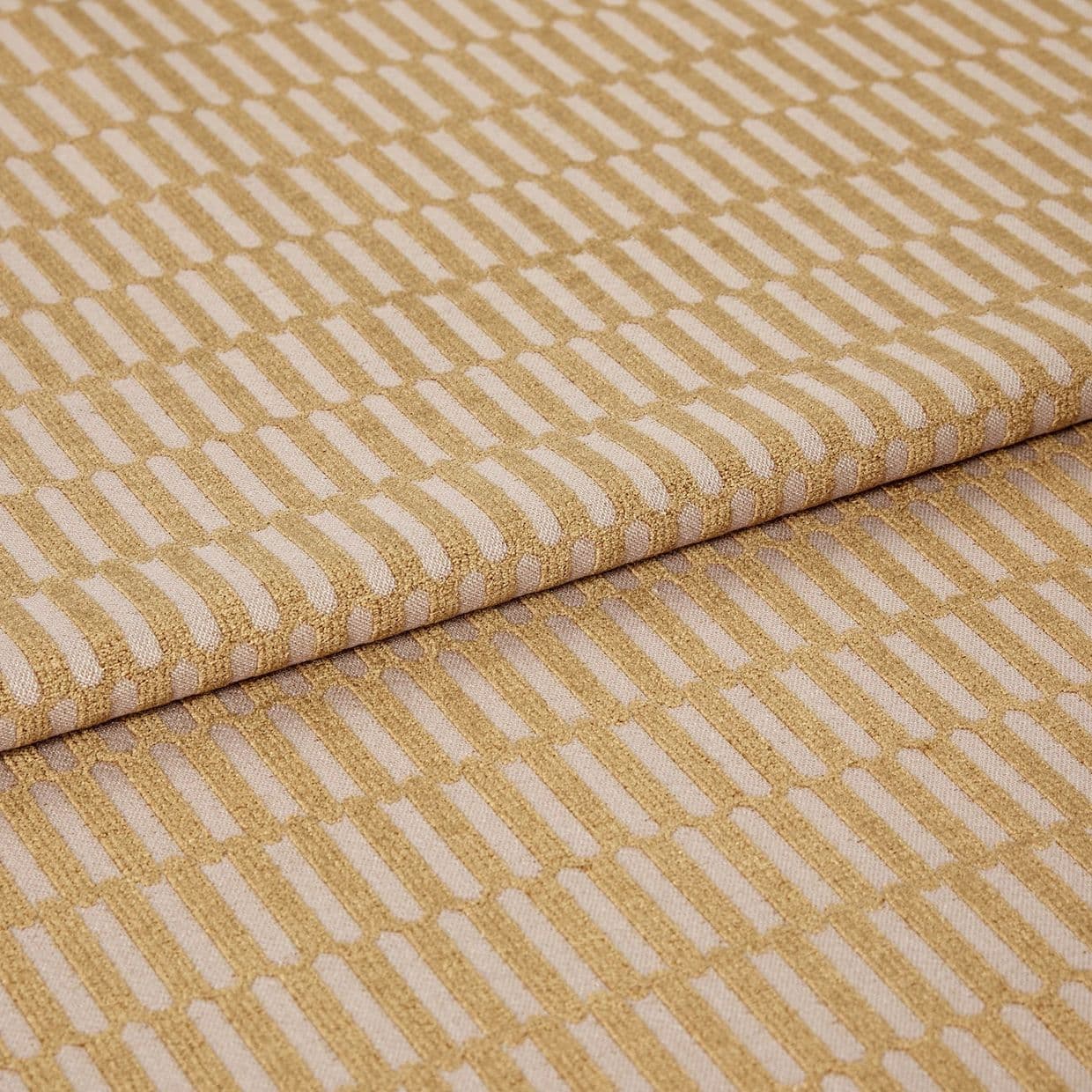 Woven upholstery fabric with a raised golden rectangular grid, folded over itself; pattern repeats diagonally across the surface, shown in a close-up, studio-lit view on a neutral background.