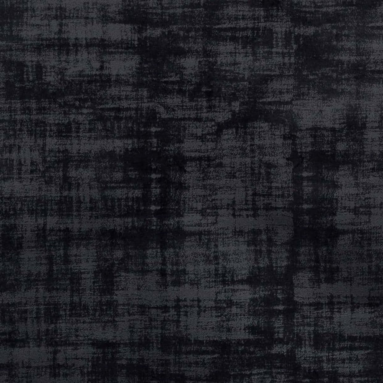 Dark charcoal fabric with a distressed, crosshatched texture (velvet-like), lying flat; displaying uneven shading and a worn appearance in diffuse, low-contrast lighting, like an upholstery or rug sample.