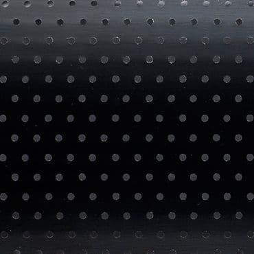 Black roller blind with regular small circular perforations â€” lowered and closed, the holes subtly admit faint light â€” set in a dim interior against a smooth background with a gentle top gradient.