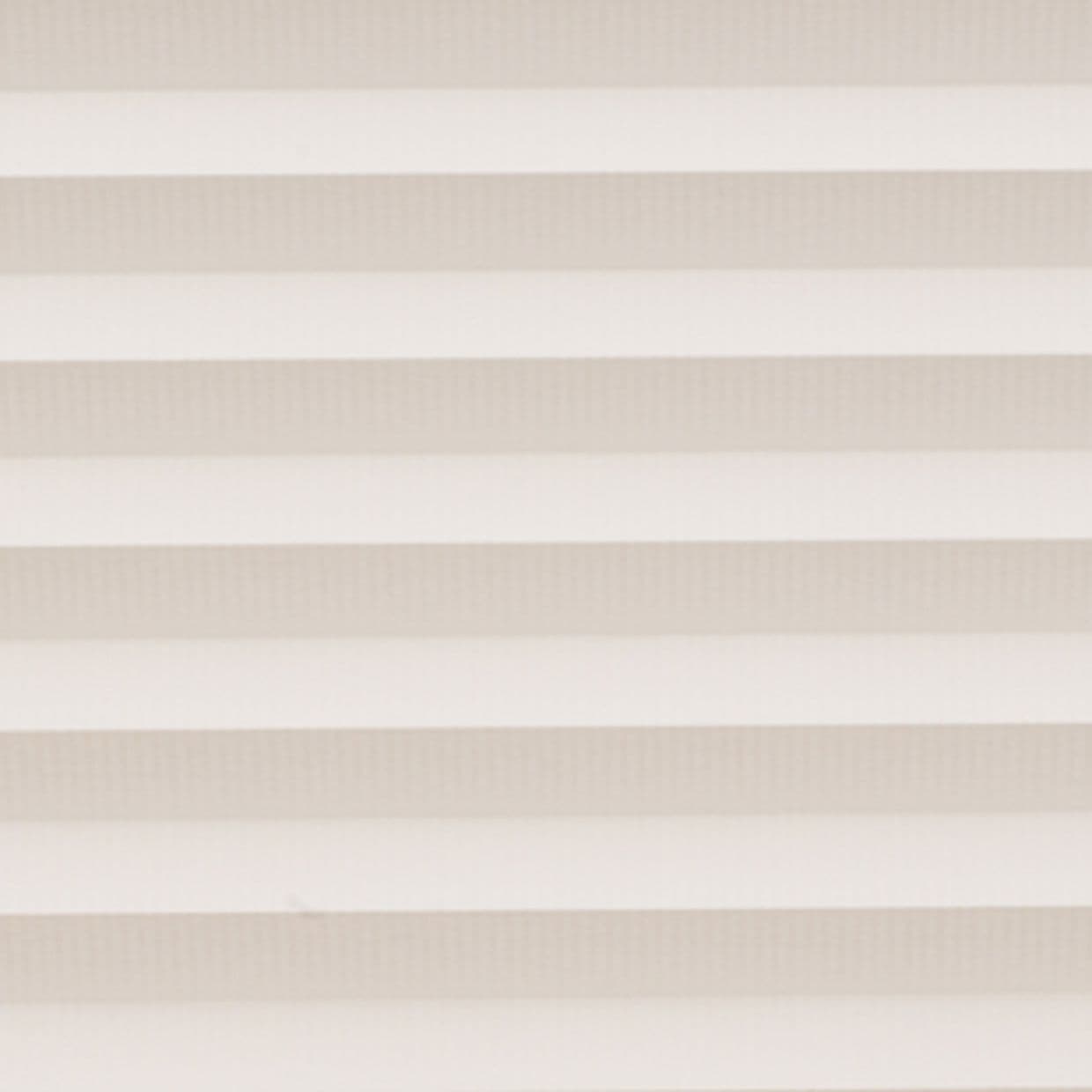 Horizontal cellular blinds with alternating beige and off-white pleats, closed and filtering soft daylight; they cover a window within a neutral interior, producing even, diffuse light and no view.