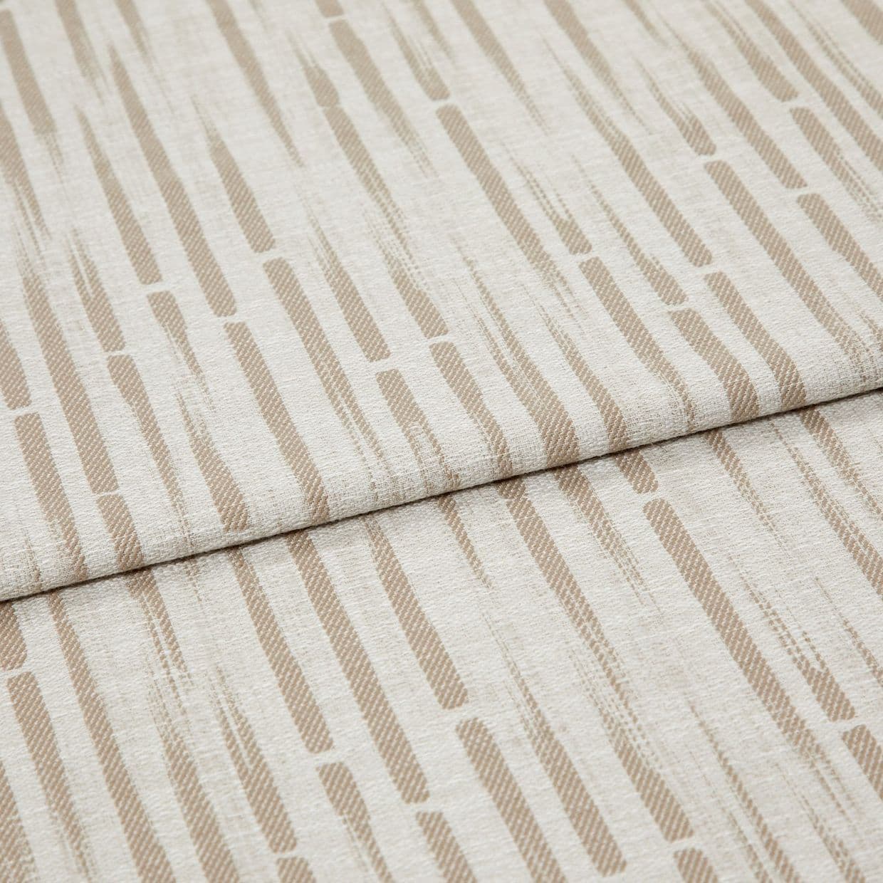Beige-and-cream patterned textile (elongated dashes) folded across the center, overlapping slightly; close-up, even soft lighting on a flat surface, resembling upholstery or drapery material.
