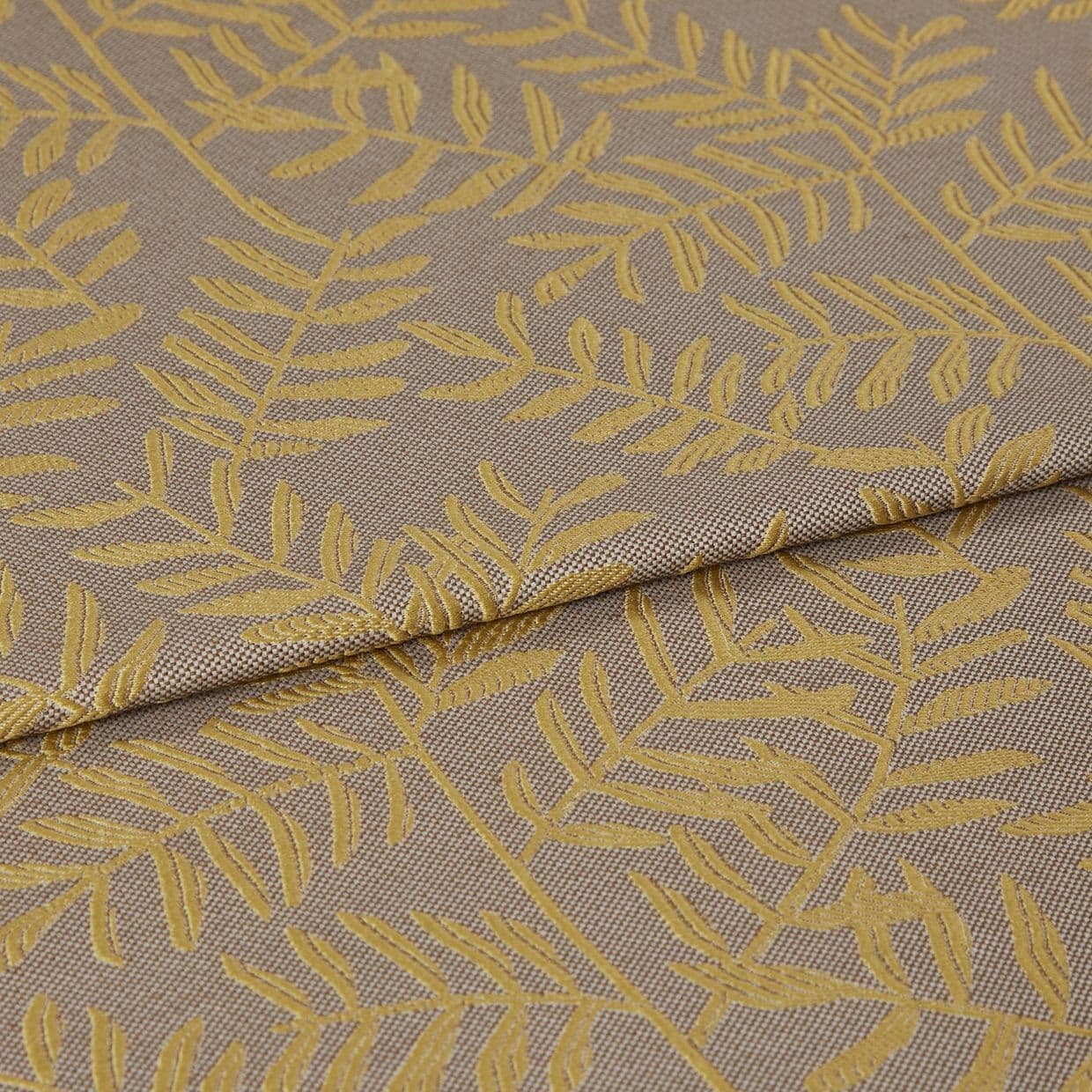 Woven curtain-like fabric with mustard-yellow leaf motif, folded once across the frame and overlapping; close-up view revealing textured taupe weave under soft, even studio lighting.