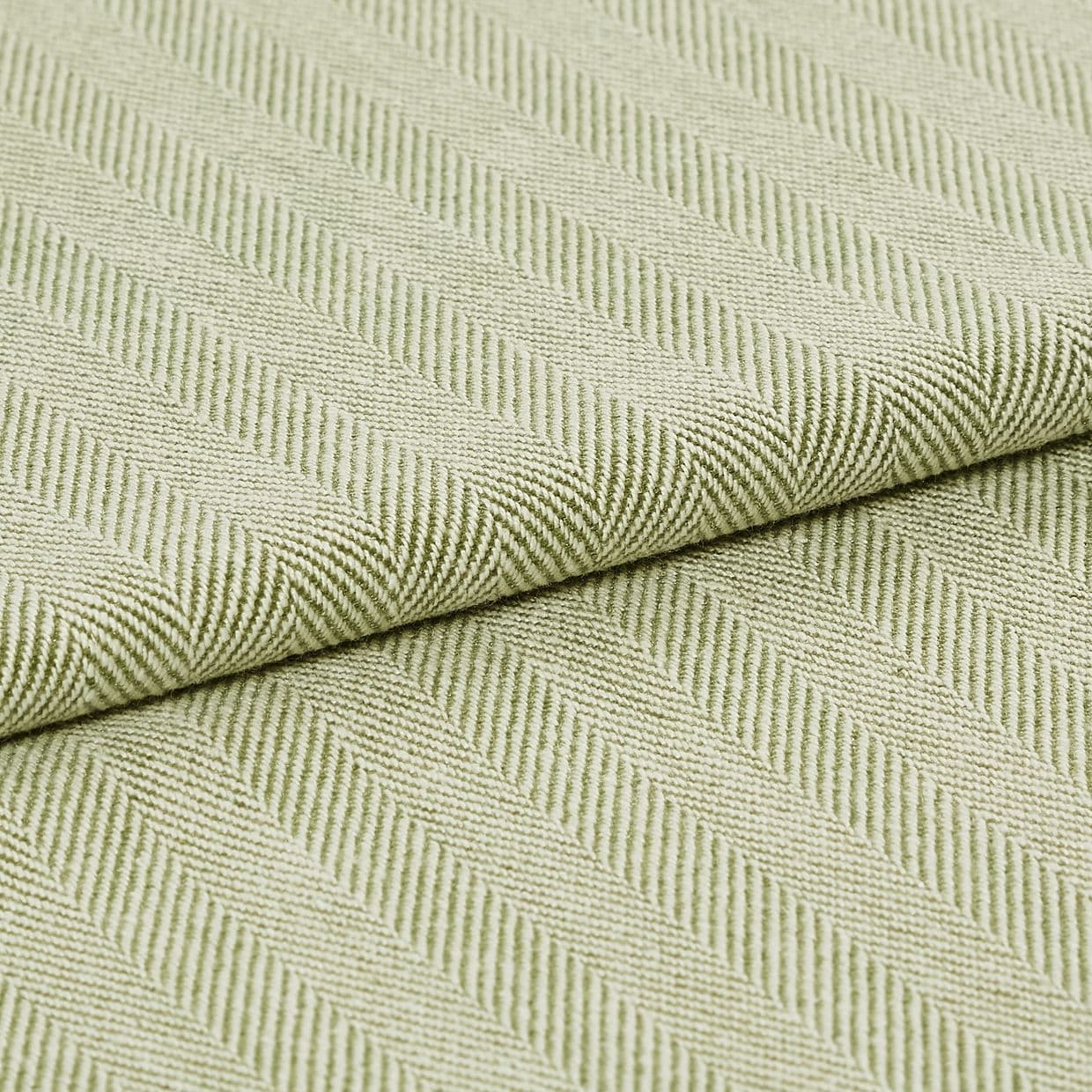 Pale green woven fabric with raised diagonal ribbed herringbone pattern, folded across the frame; the fabric displays pronounced texture and ridges under soft, even studio lighting in a close-up view.
