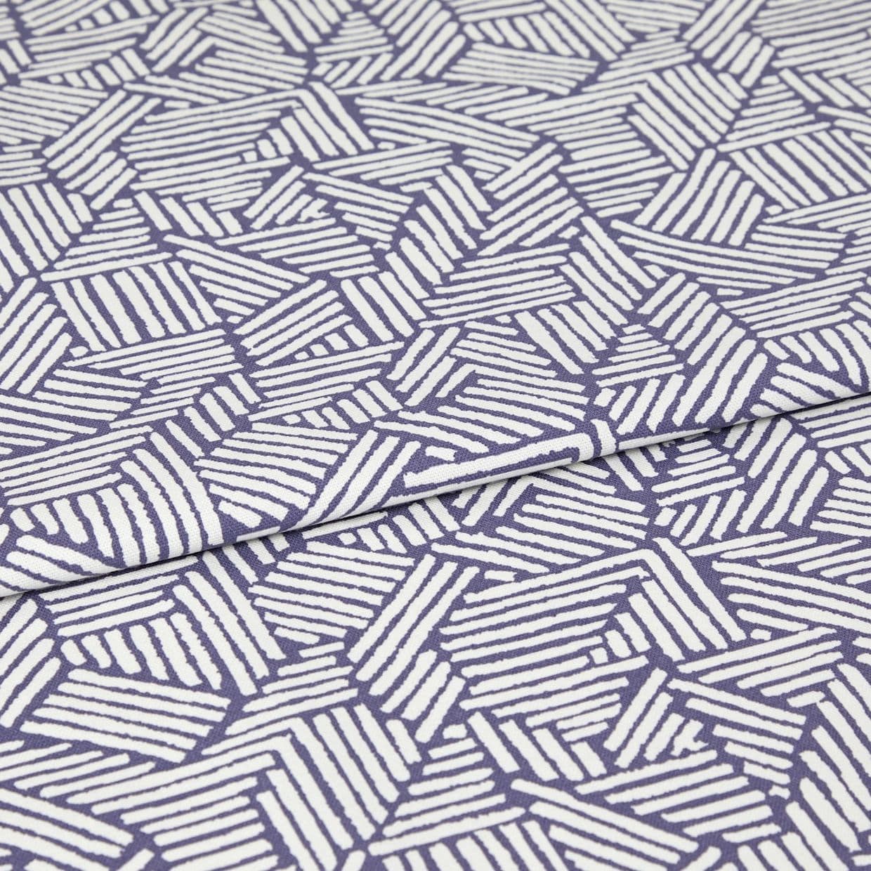 Folded fabric with purple background and white hand-drawn diagonal stripe hexagon pattern; the cloth is folded once with a visible overlap; close-up on a flat surface under even studio lighting.