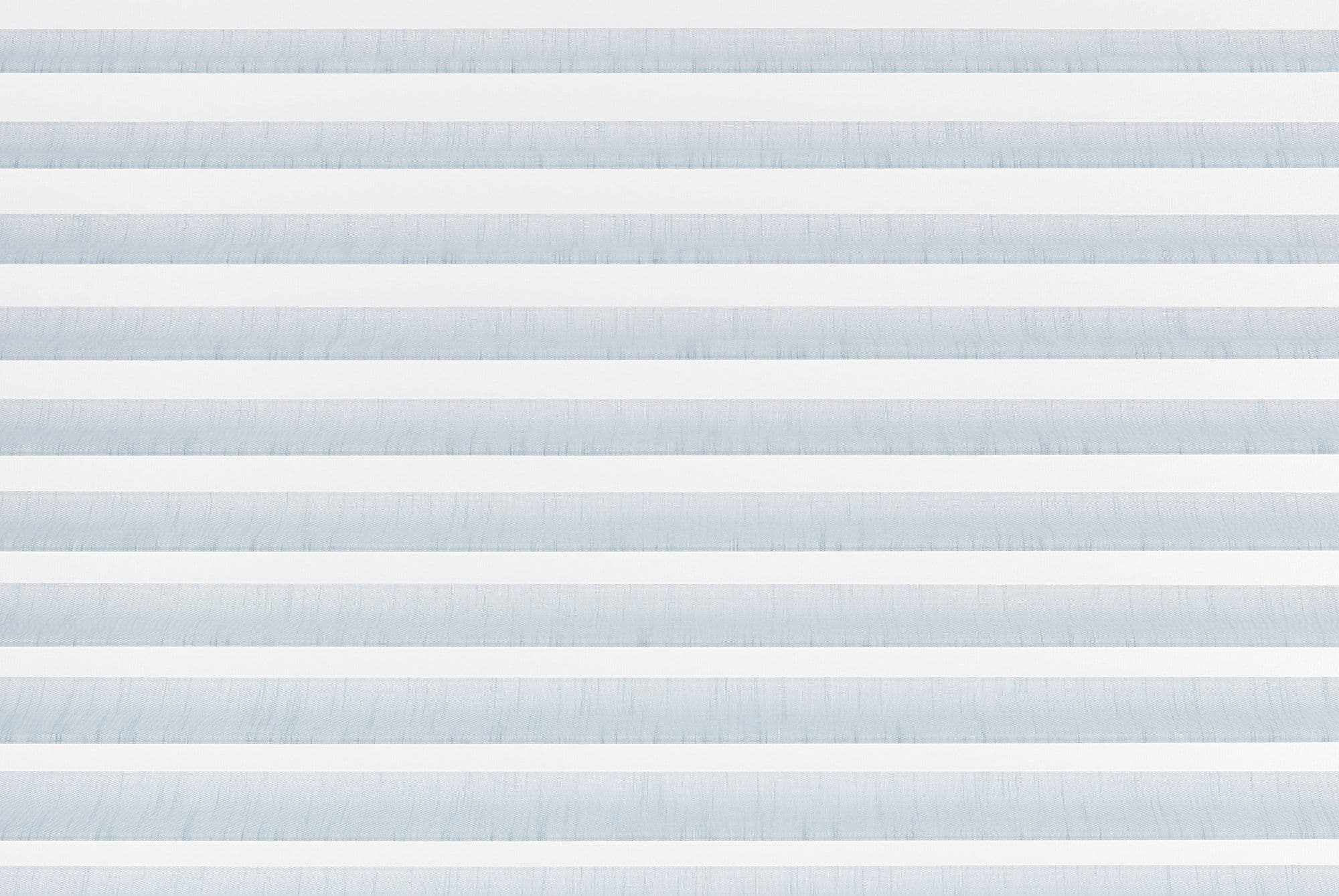 Horizontal zebra blinds with alternating white opaque and pale blue translucent fabric filling the frame, closed and filtering soft daylight, in a minimal interior with no visible view.