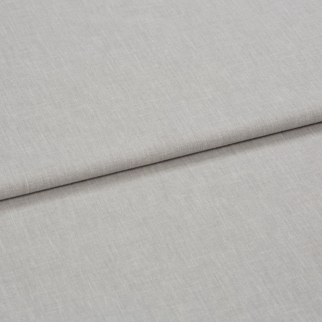 Light gray linen-like fabric folded horizontally, creating a soft crease; close-up shows fine woven texture under even neutral lighting, appearing as a fabric sample or upholstery material on a flat surface.