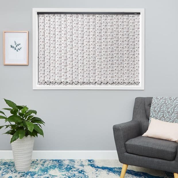 Sheer white lace curtain, fitted inside the window frame with floral pattern and scalloped hemâ€”hanging closed, softly filtering daylight in a light-gray living room with gray armchair, potted plant, and blue rug.