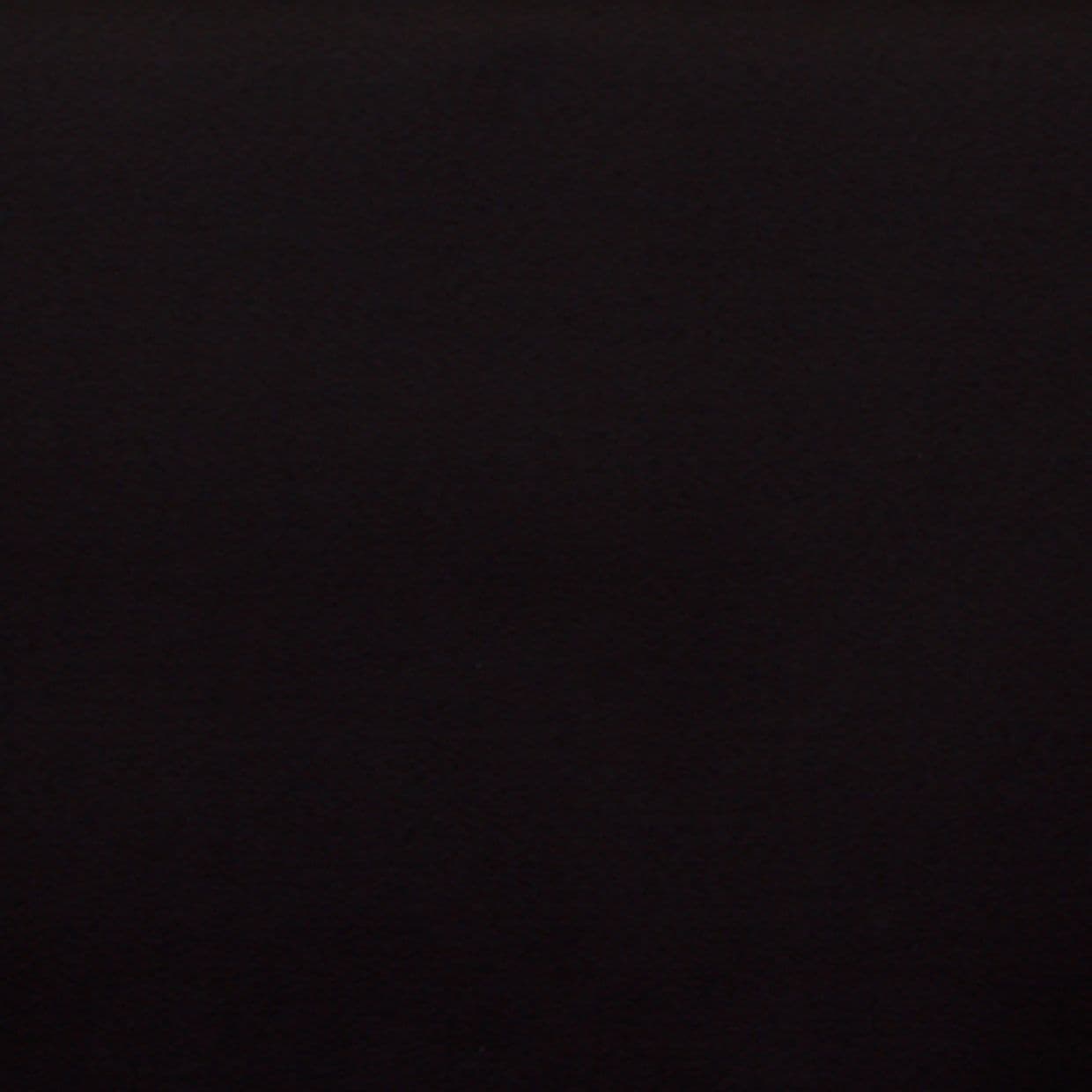 Matte dark wall centered in frame, flat and featureless; absorbing light and appearing unlit; context: dim indoor scene with no visible details or furnishings.