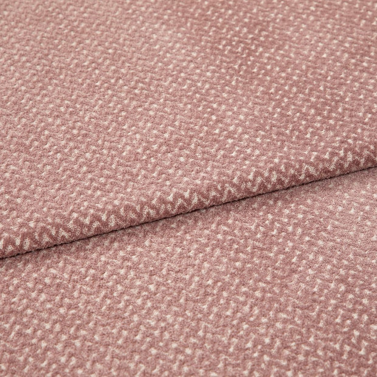 Textured woven upholstery fabric, dusty rose with small creamy fleck pattern, folded in two layers; lying flat on a neutral surface under soft, diffuse studio lighting for detail display.