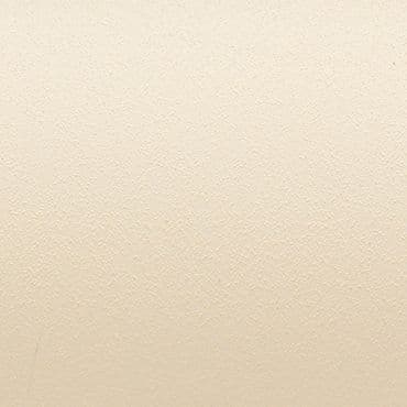 Beige stippled wall surface showing a fine, pebbled texture; evenly lit and uniformly colored; closely framed, neutral interior background with no visible fixtures, shadows, or distinguishing features.