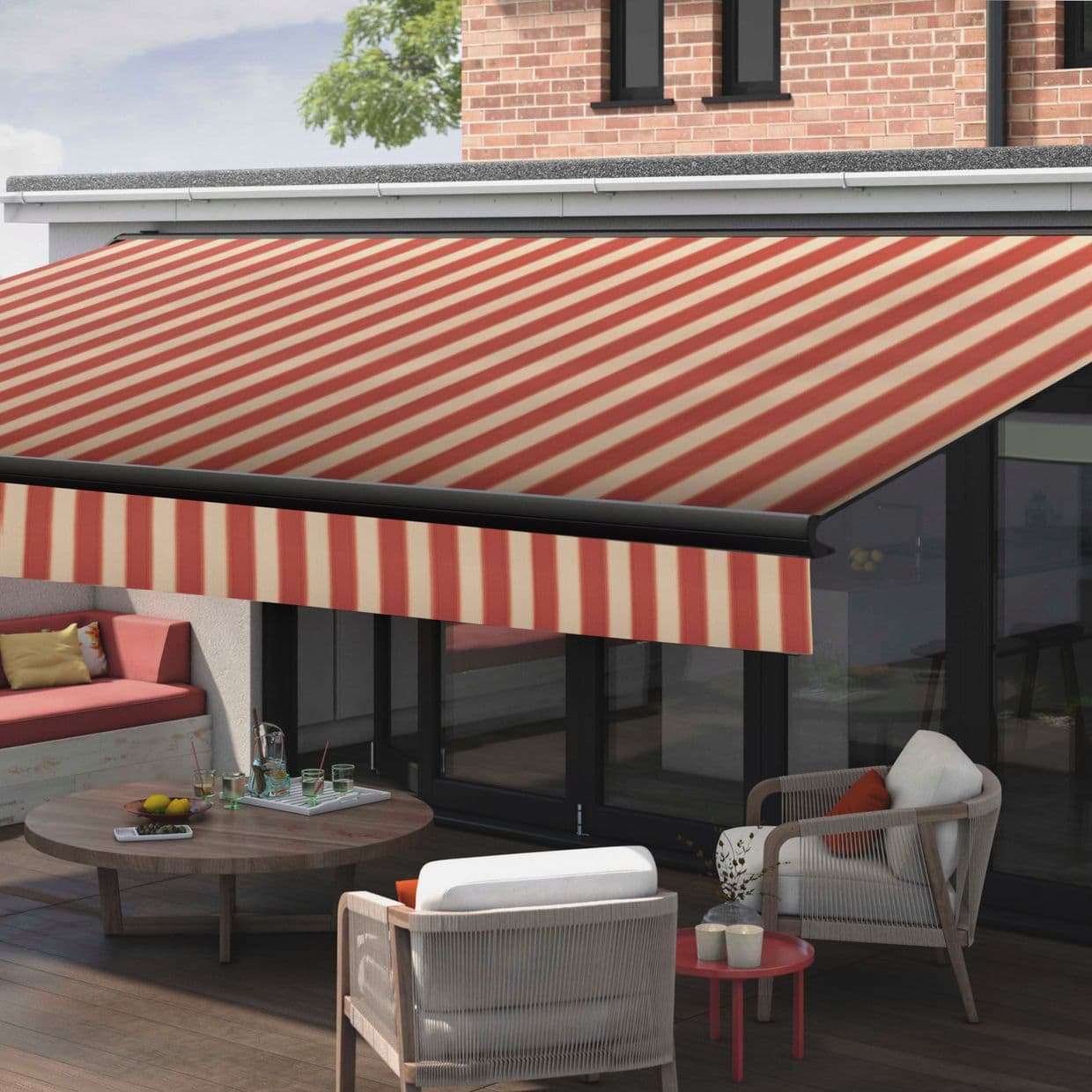 Striped red-and-cream retractable awning, extended from a house above glass sliding doors, diagonal-patterned fabric with valance, shading a modern outdoor patio with seating, wooden table, and brick upper wall.