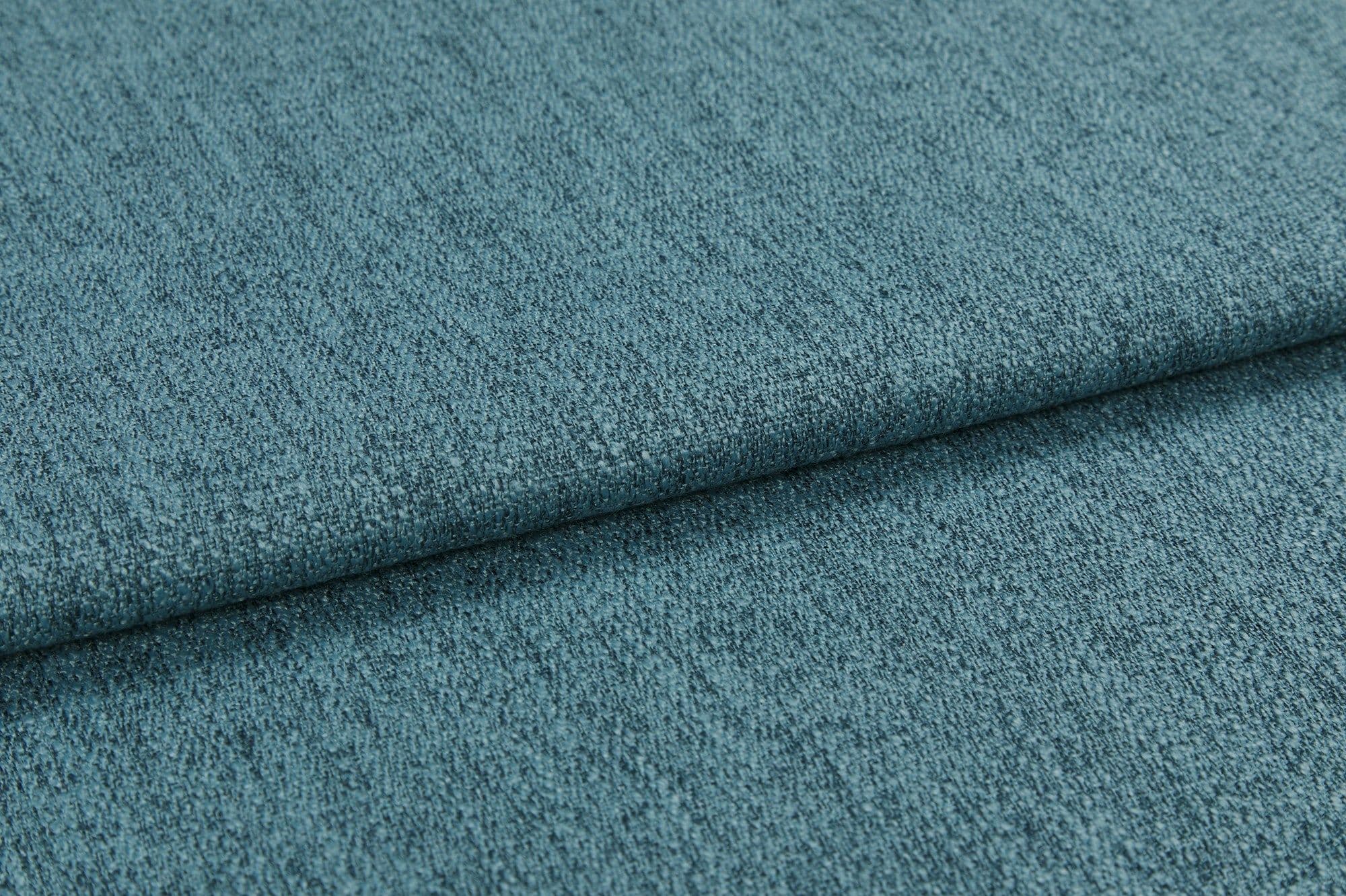 Teal textured upholstery fabric, folded into overlapping layers with visible weave and nap; lying flat as a close-up sample under soft diffuse lighting, showing subtle color variation.