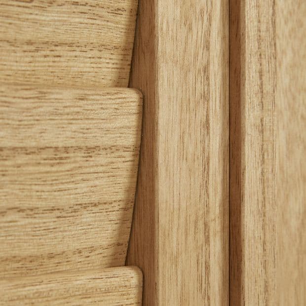 Light oak louvered shutter panel, close-up showing a slat and frame with visible grain; slats fitted and closed within the frame, warm interior lighting.