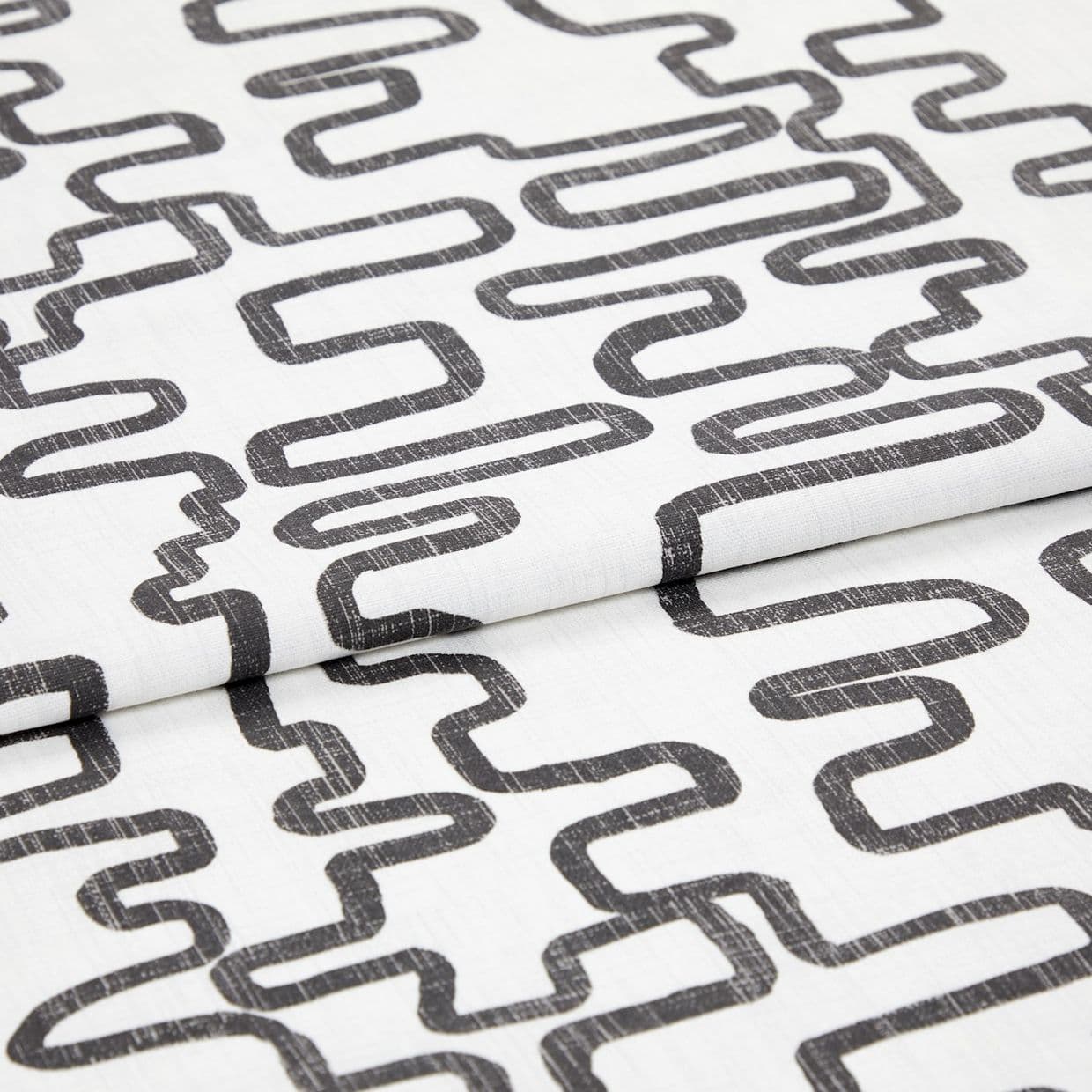 White woven fabric printed with charcoal, distressed looping-rectangle pattern, folded to show overlapping layers; studio close-up with even soft lighting and neutral background.