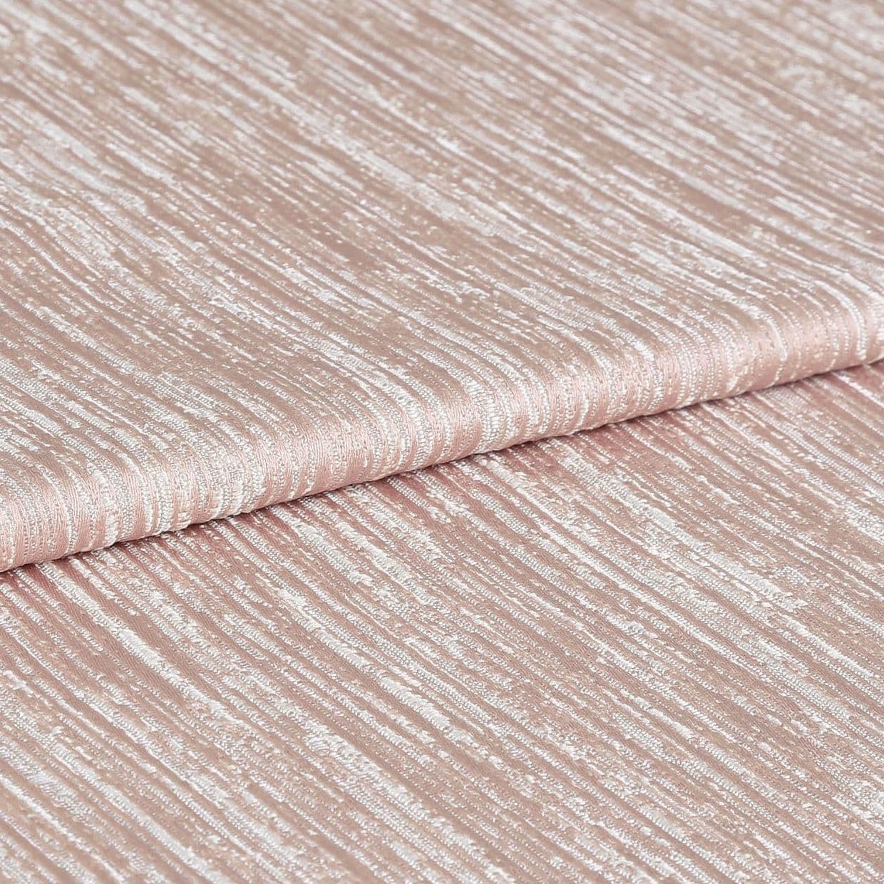 Shimmering, ribbed blush-pink fabric folded once, displaying horizontal crinkled texture and metallic sheen; close-up studio view with soft, even lighting emphasizing the tactile surface.