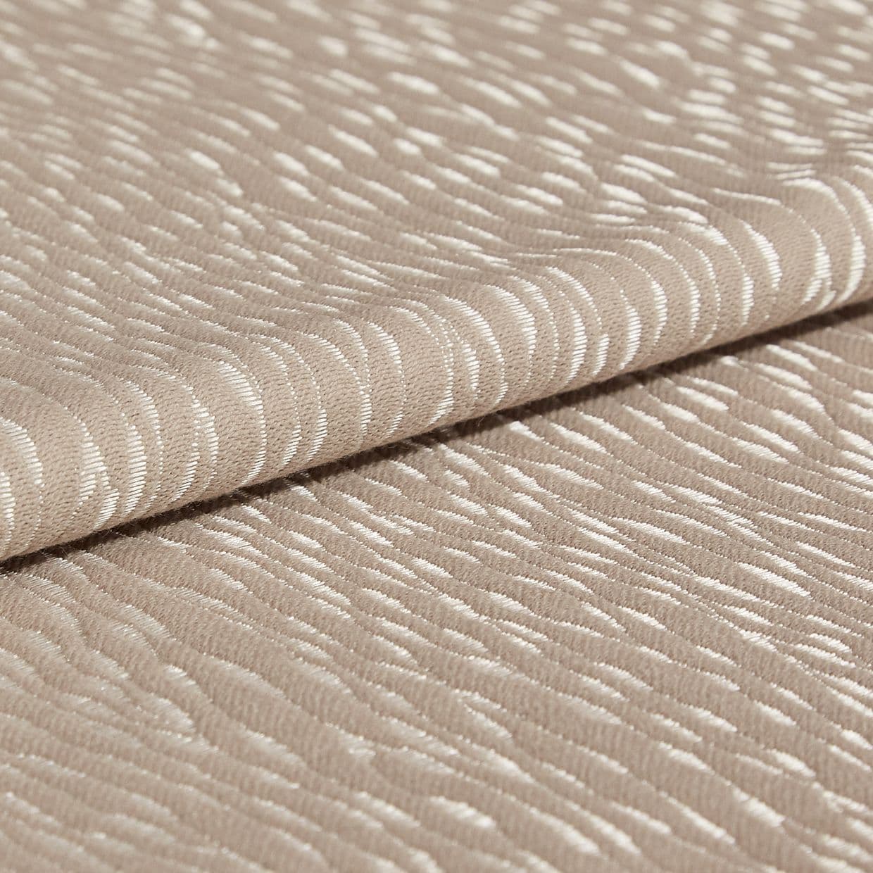 Beige jacquard fabric with glossy, raised crescent pattern; folded once across the frame, overlapping edges; close-up studio view with soft, diffuse lighting emphasizing the textured sheen.