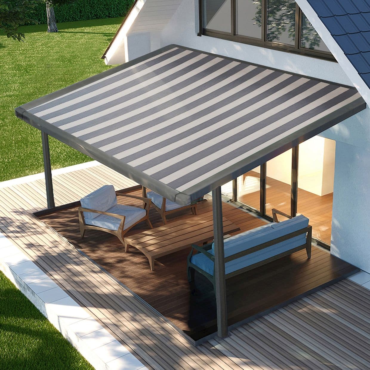 Gray-and-white striped awning mounted above glass doors on two metal posts, extended and shading a wooden deck patio with lounge chairs and a sofa; sunny lawn beyond.