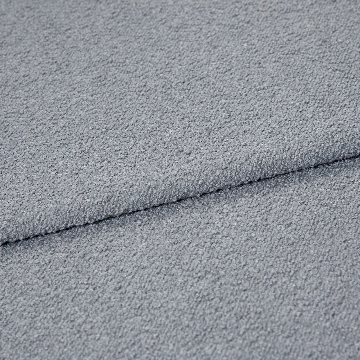 Light-gray bouclÃ© fabric folded once, showing pebbled loop texture; close-up macro view under soft, even lighting on a neutral surface, emphasizing tactile, cozy upholstery material.