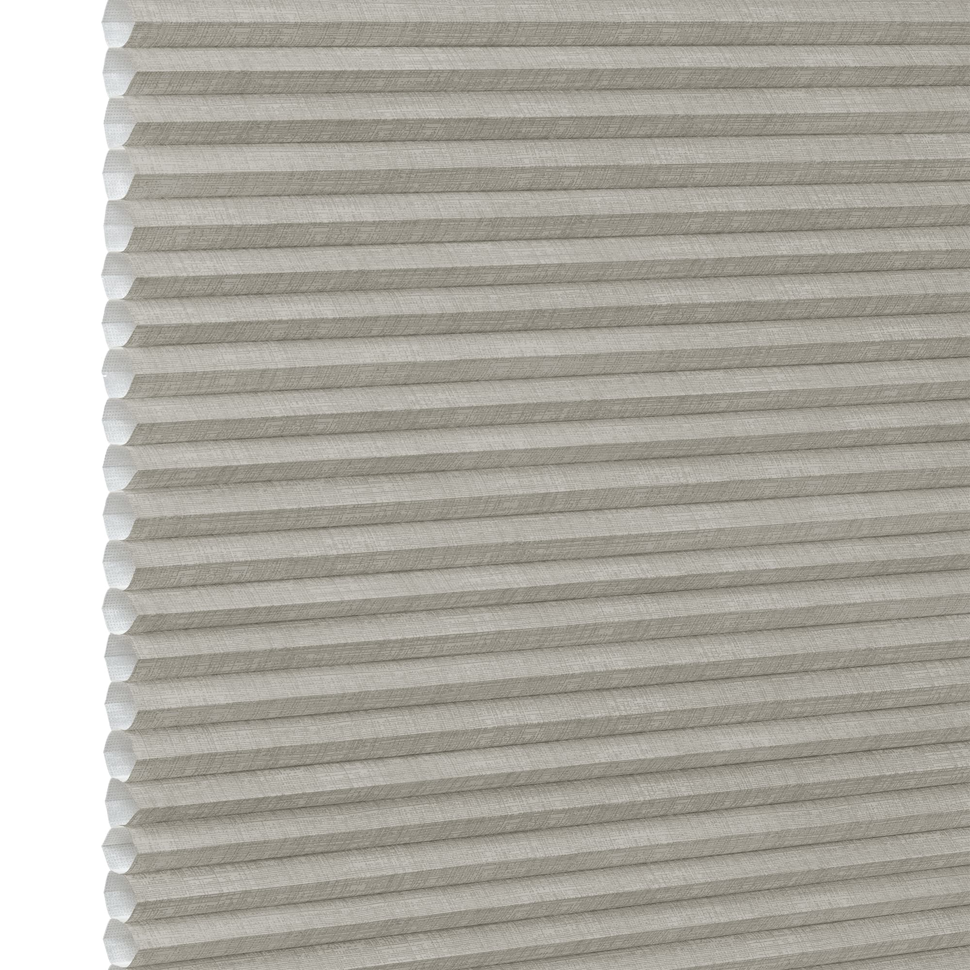 Honeycomb cellular fabric blind with horizontal pleats and textured beige finish, fully lowered and closed, diffusing soft light; set against a neutral, evenly lit wall with narrow white margin left.