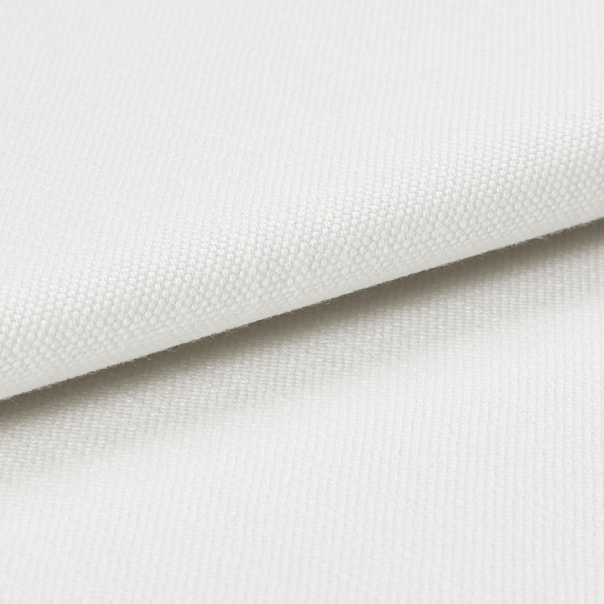 White canvas-like fabric folded diagonally, displaying a fine woven texture and overlapping edge; close-up studio view with soft, even lighting and neutral background emphasizing the weave detail.
