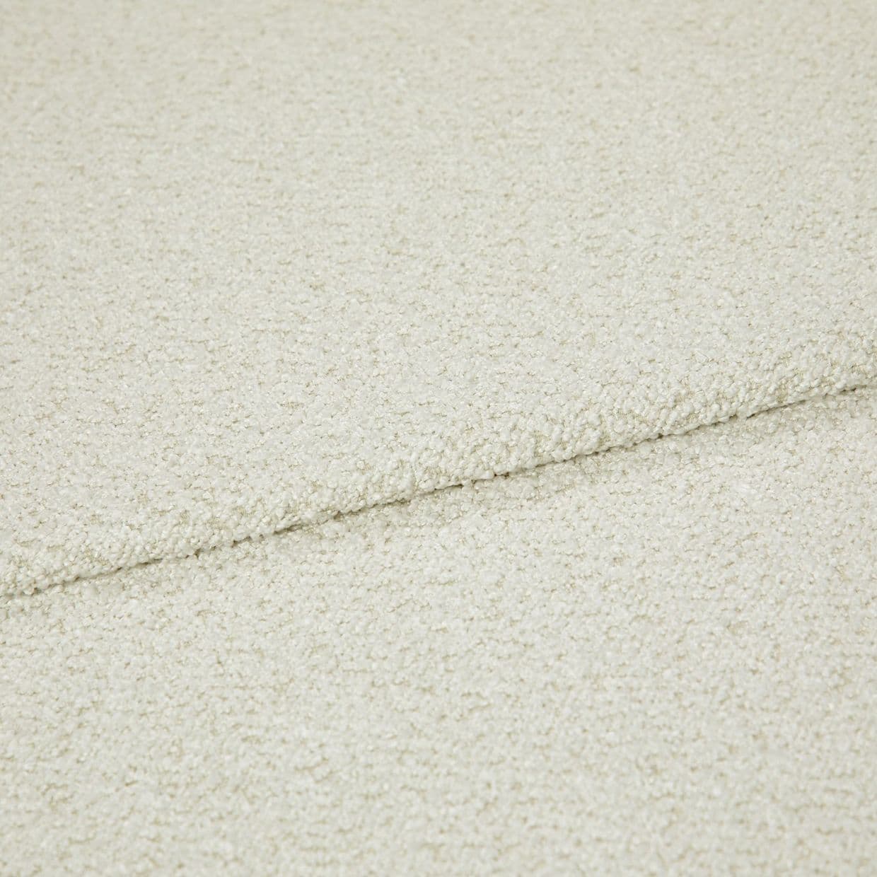 Cream bouclÃ© fabric folded into overlapping layers, showing a horizontal seam; close-up view with soft, even lighting emphasizing the looped texture in a neutral studio setting.