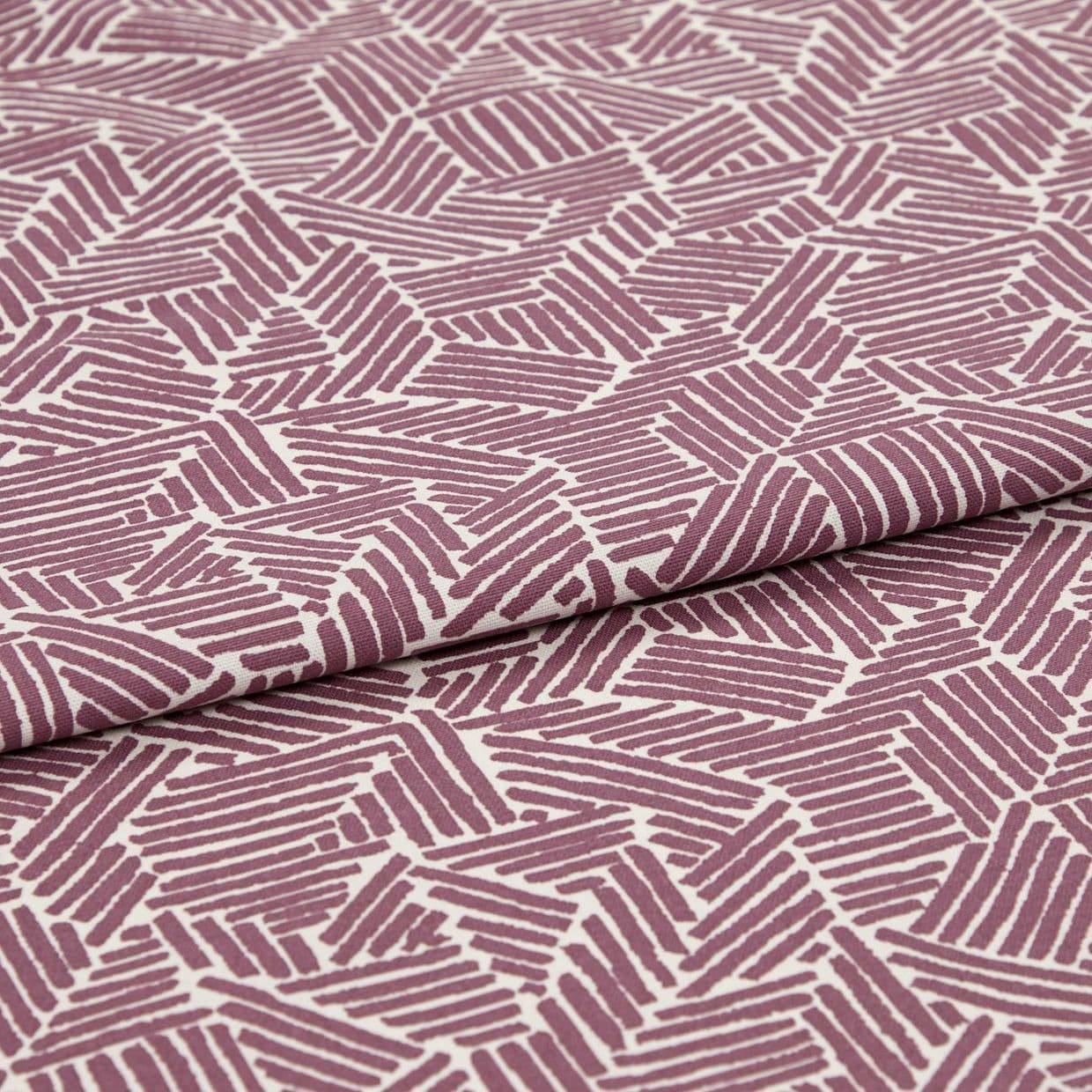 Folded printed cotton fabric with mauve geometric stripe blocks, repeating irregular parallelograms; folded edge runs diagonally, fabric lies flat under soft studio lighting for a close-up textile view.