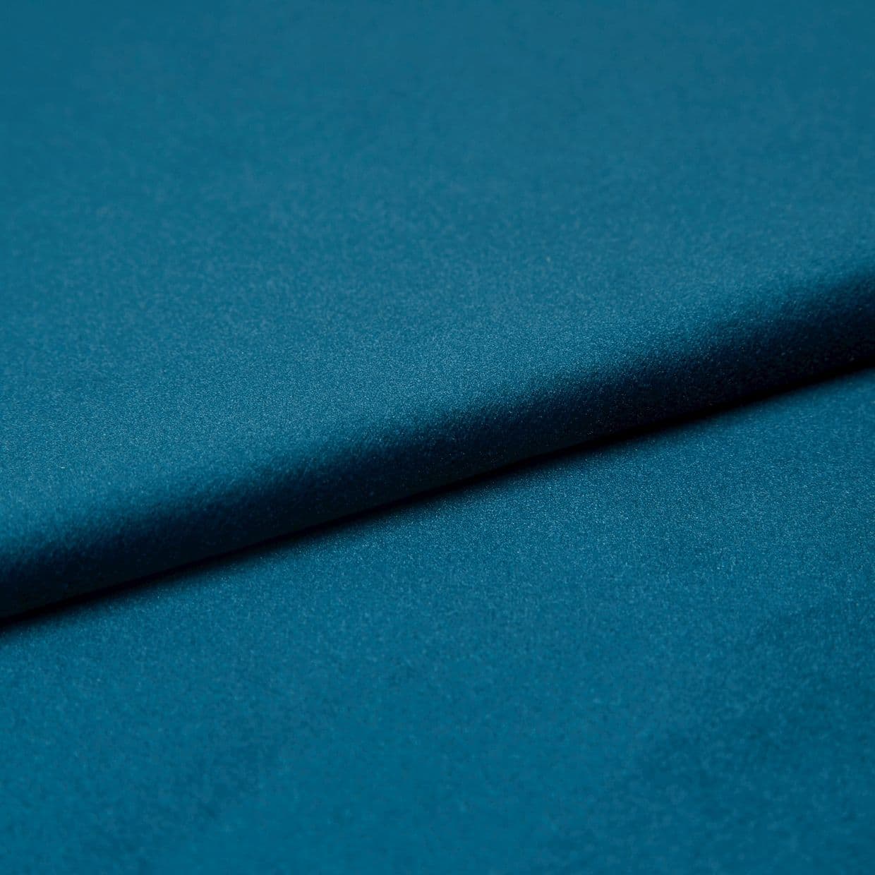 Teal satin fabric, folded diagonally with a soft sheen and subtle texture; fold casting a gentle shadow, close-up studio view with even lighting emphasizing the smooth surface.