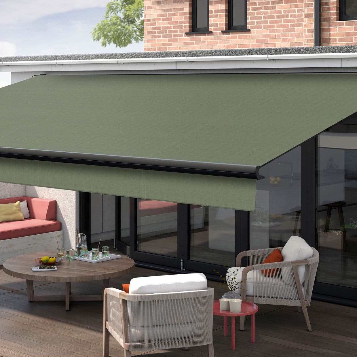 Green retractable fabric awning, fully extended with black front bar, shading ground-floor glass patio doors; outdoor terrace with wicker armchairs, round coffee table, cushioned bench and brick faÃ§ade in daylight.
