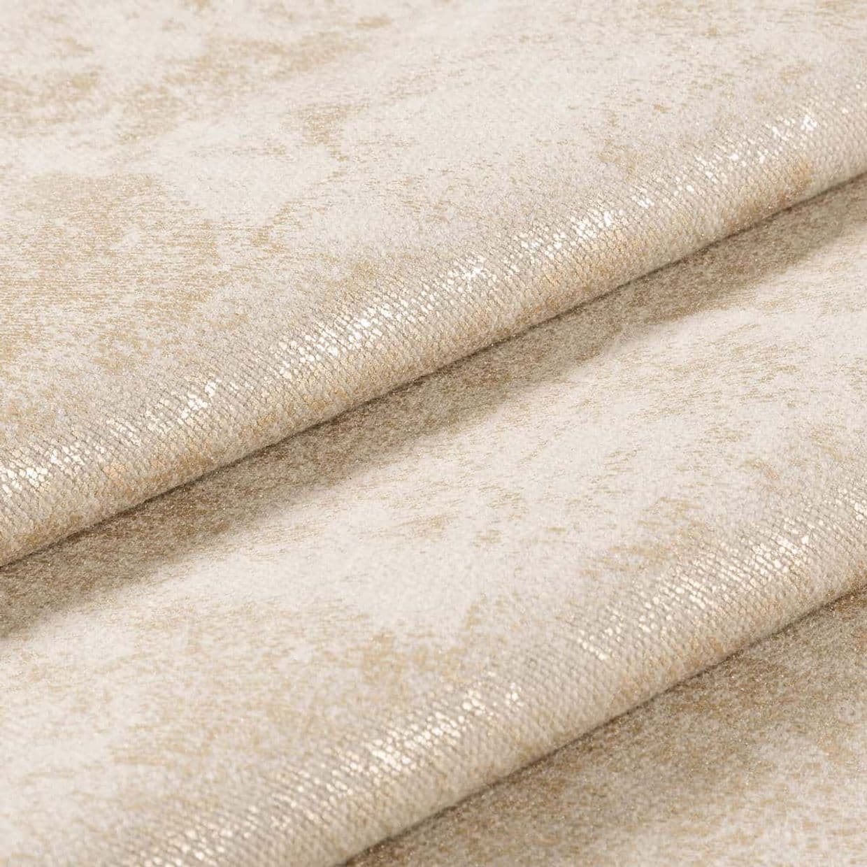 Folded beige upholstery fabric with subtle gold metallic sheen and small-scale textured weave, overlapping diagonal folds shimmering under soft light, macro studio close-up with neutral background.