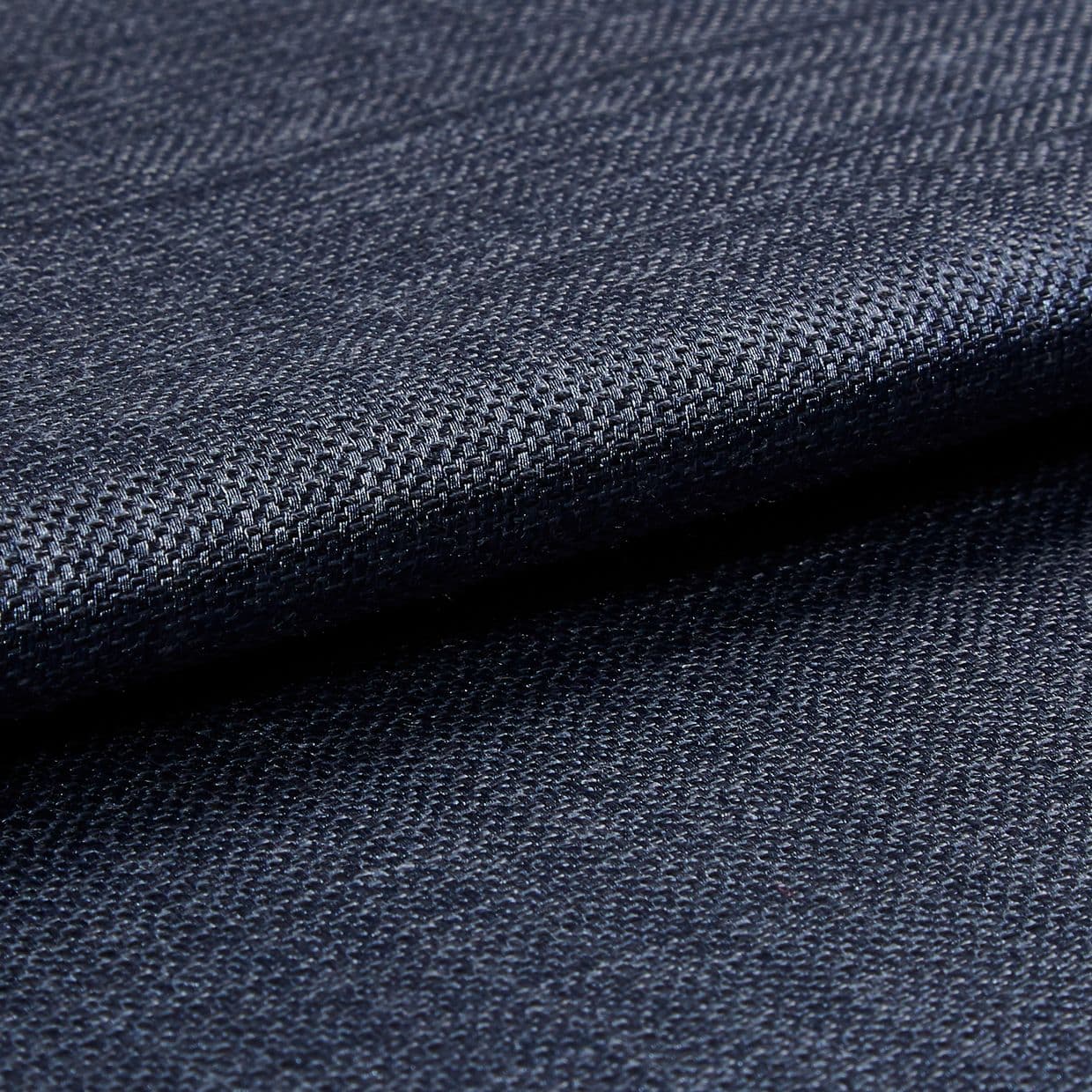 Dark navy woven fabric, tightly woven and folded over itself; its textured basket weave catches a subtle sheen, shown in a close-up macro view with soft, even lighting.