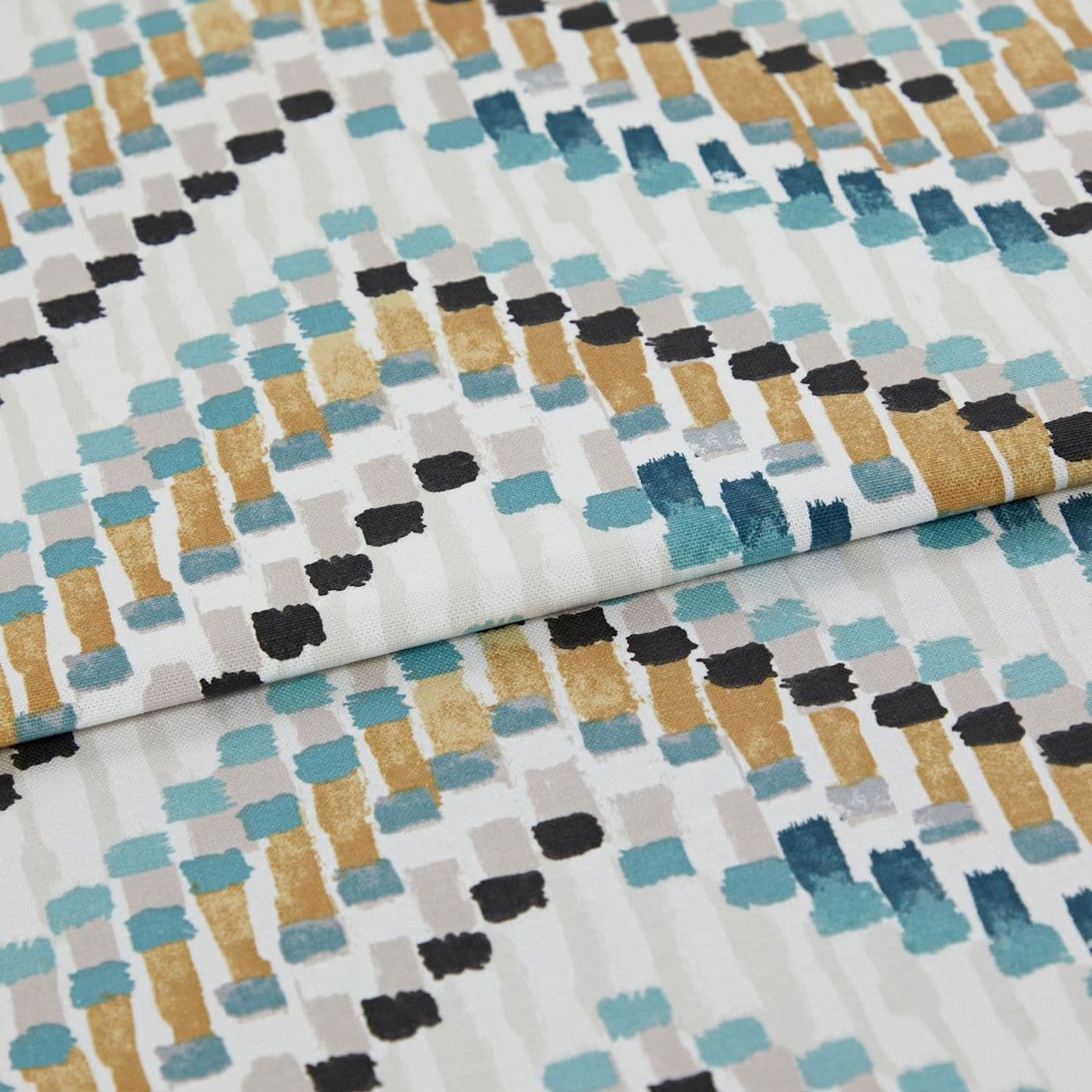 Fabric with abstract rectangular brushstroke pattern (teal, mustard, black, gray) â€” folded across the frame â€” close-up studio shot showing textured cotton/linen surface and even soft lighting.