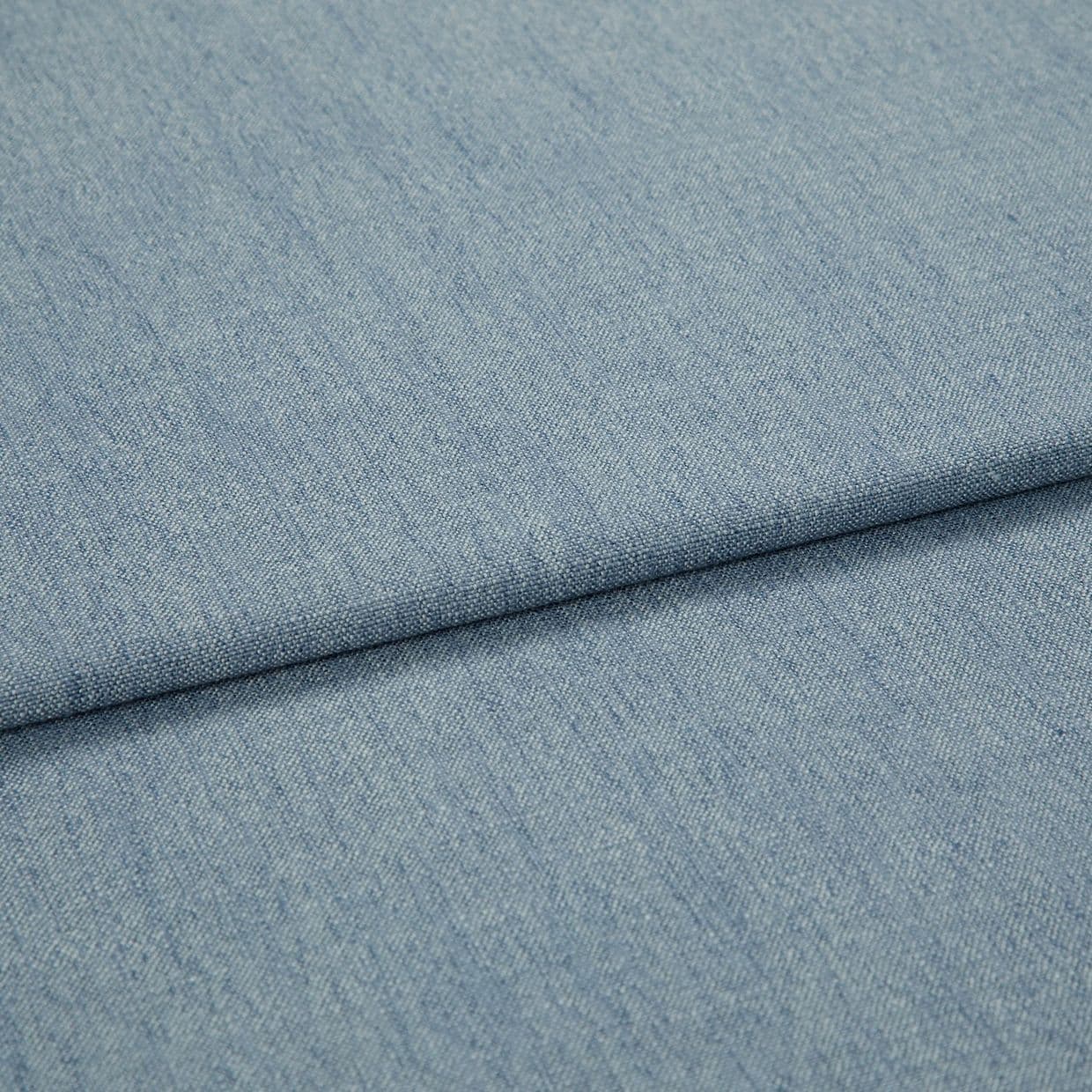 Light-blue woven denim-like fabric, folded diagonally with a shallow overlapping fold; surface shows fine weave and subtle striations, close-up view with soft, even lighting.