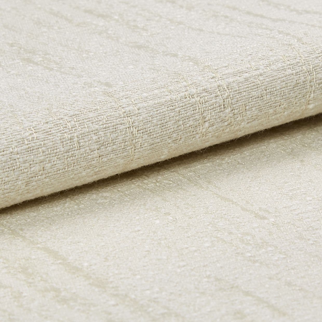 A folded beige woven fabric with subtle sheen and raised grid texture, layered over matching fabric; close-up studio view with soft, diffuse lighting on a neutral surface.