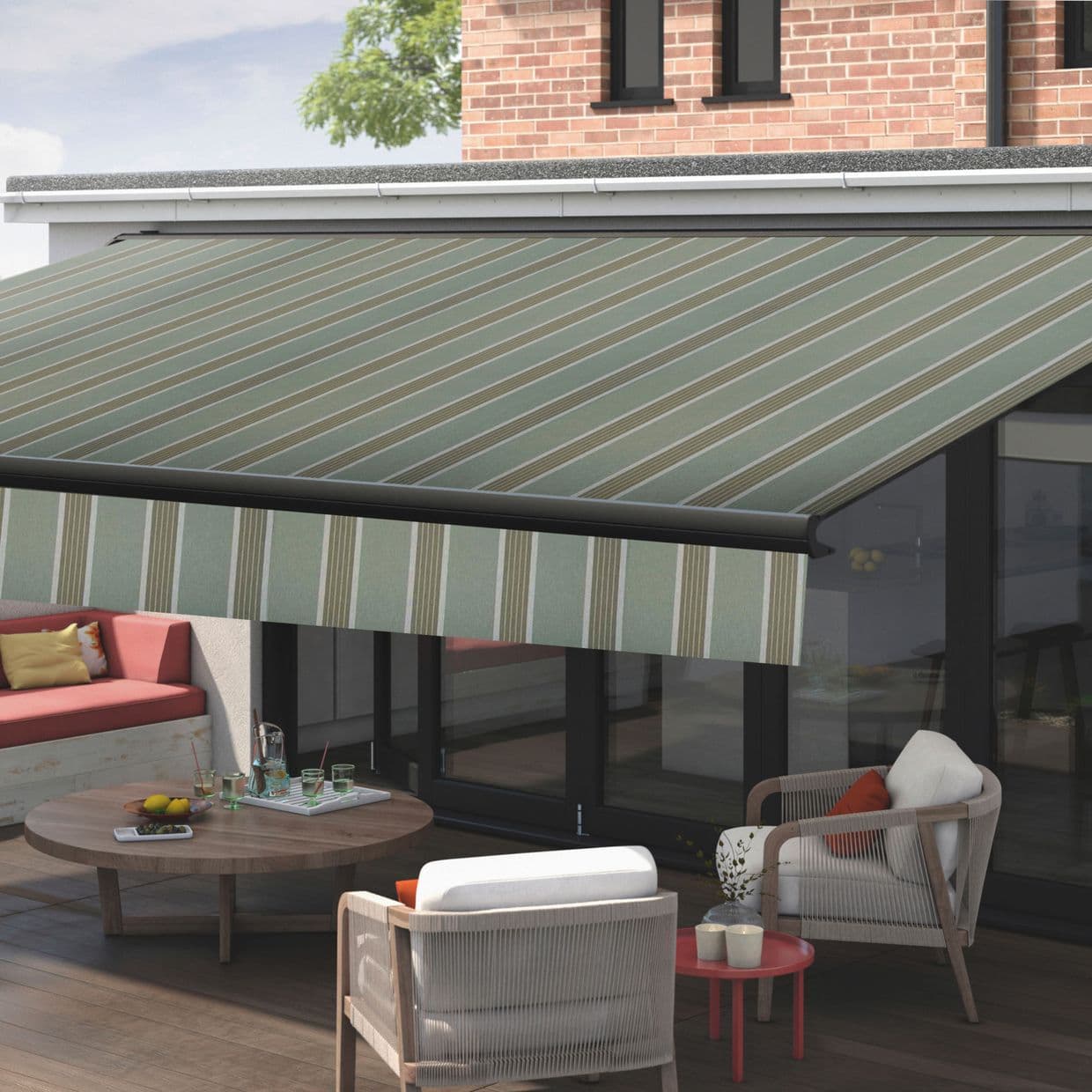 Green-and-beige diagonal-striped retractable awning with striped valance, fully extended over glass doors; shading a sunlit patio with wooden table, cushioned chairs, and a brick upper wall backdrop.