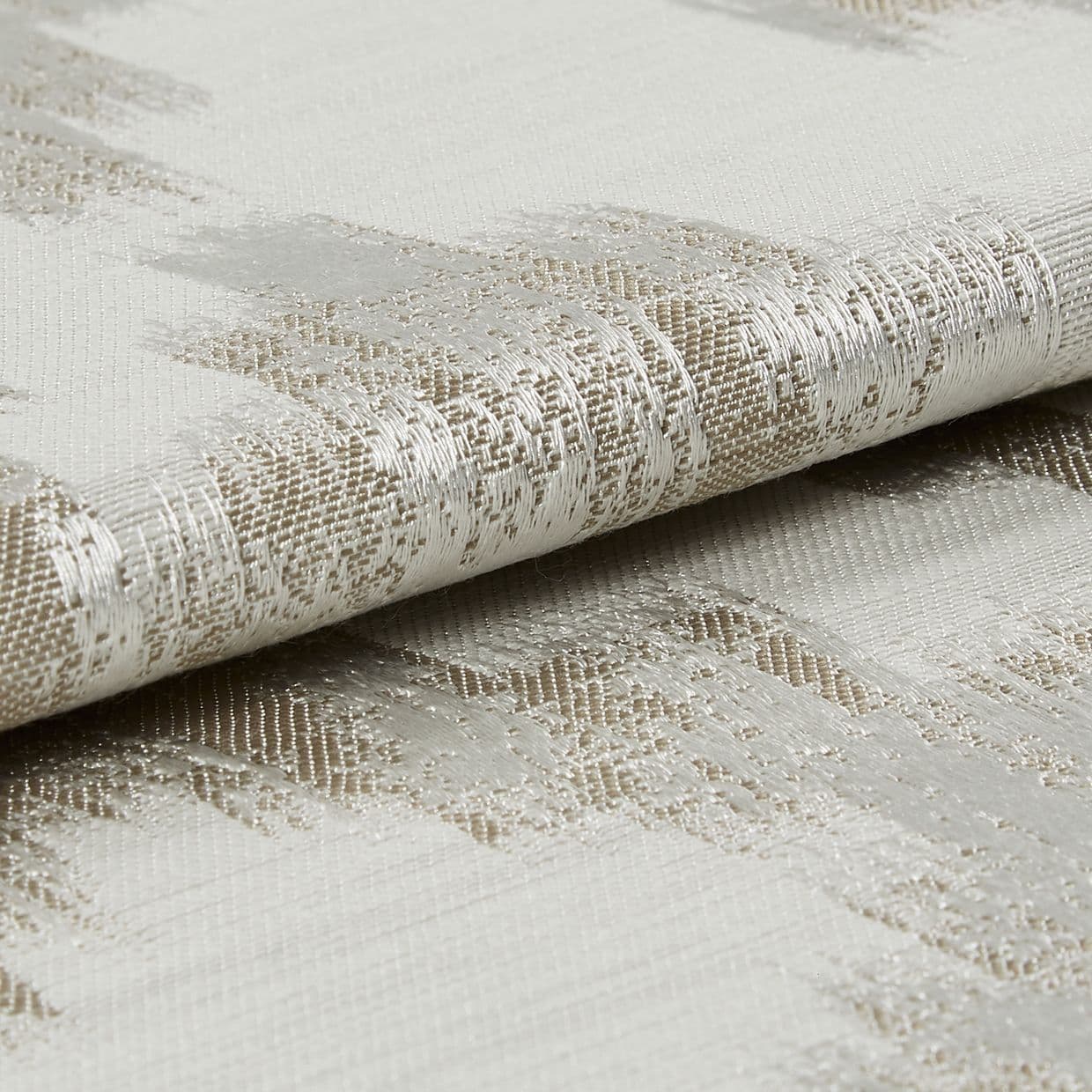 Woven curtain fabric, folded to reveal a metallic-thread abstract pattern and textured weave, reflecting light; close-up, neutral studio lighting.