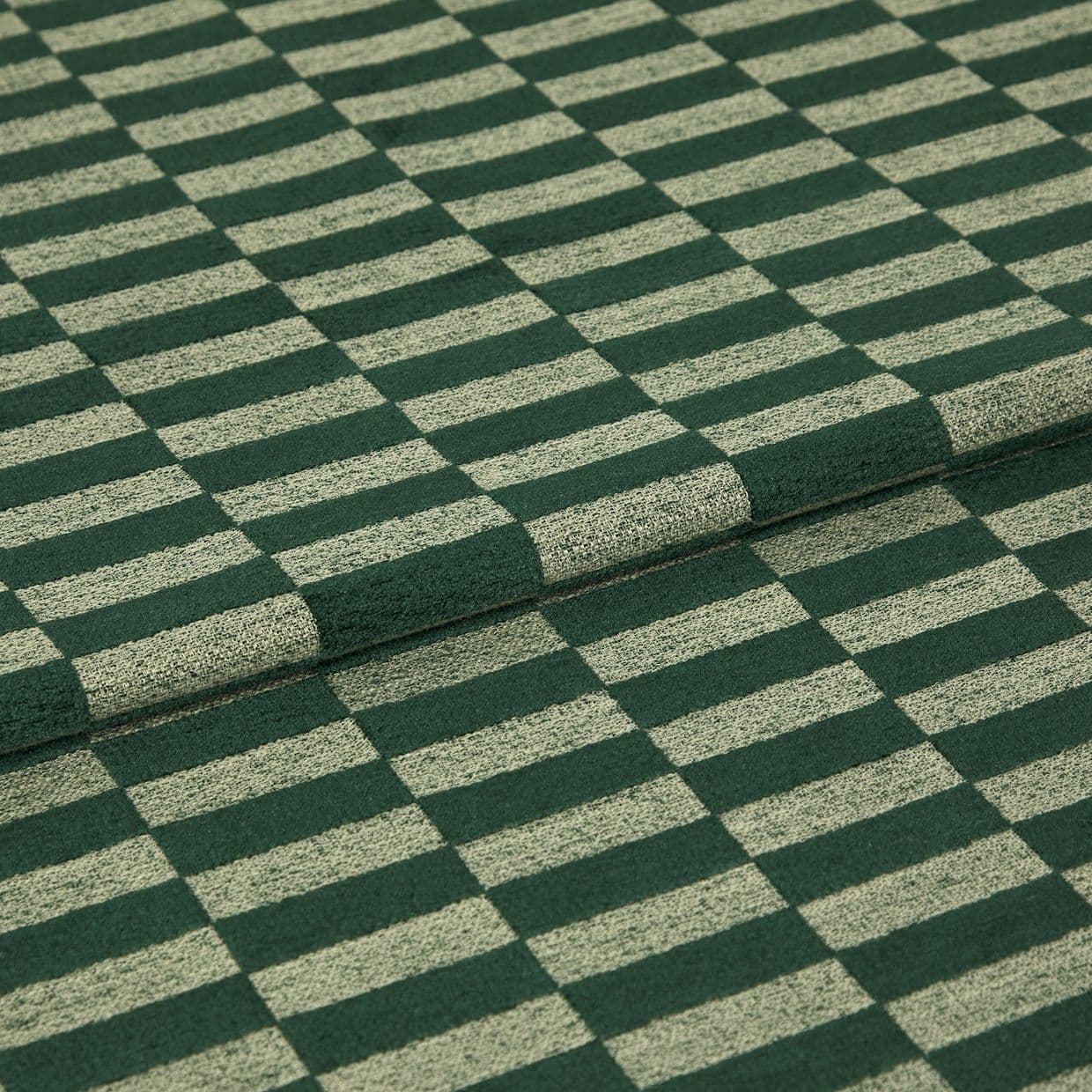 Green-and-beige rectangular checkered fabric folded in two, showing textured loops; laid flat in a close-up studio shot, highlighting the woven pattern and soft upholstery or rug material under neutral lighting.