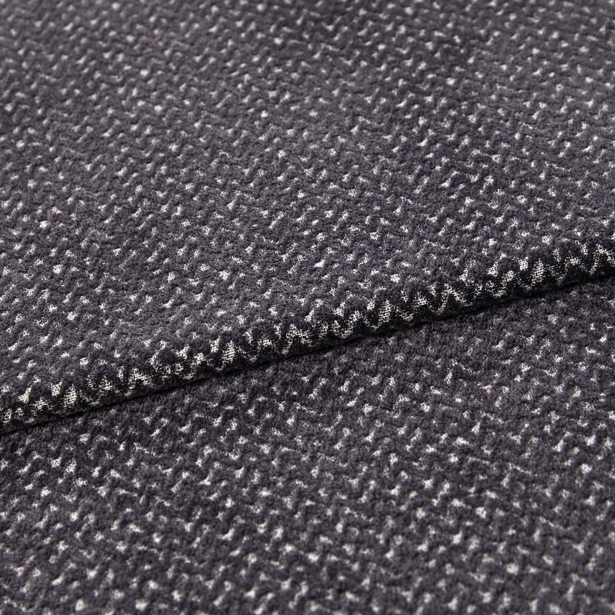 Folded dark gray woven fabric (small white flecked texture) â€” layered edge overlapping â€” close-up studio view highlighting soft pile and subtle zigzag pattern.