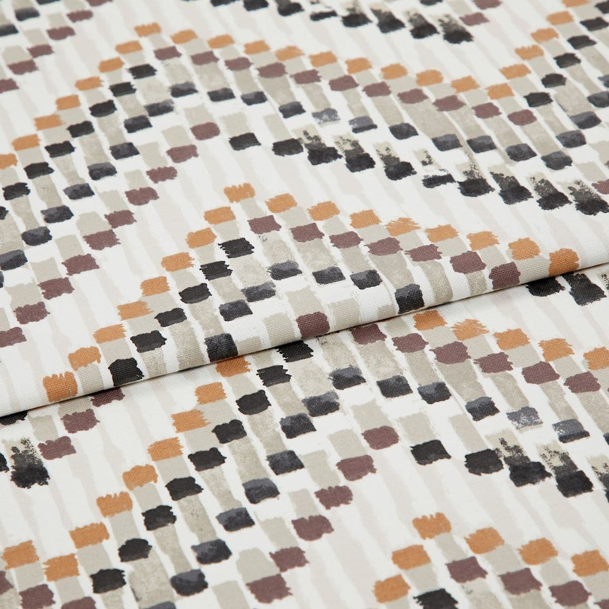 Patterned fabric swatch with staggered brushstroke square motifs in orange, brown, gray and black â€” folded and layered â€” close-up flat-lay on a neutral, evenly lit studio background.