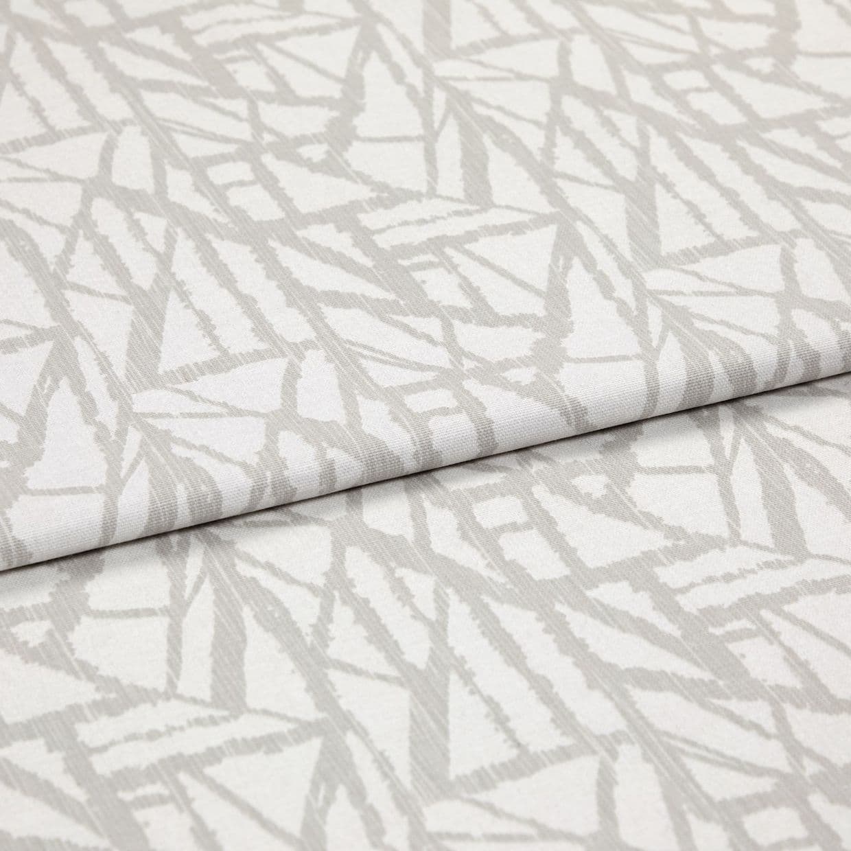 Neutral cream curtain fabric with pale grey abstract linear pattern, folded in overlapping layers; close-up studio view showing woven texture, soft even lighting and shallow depth of field.