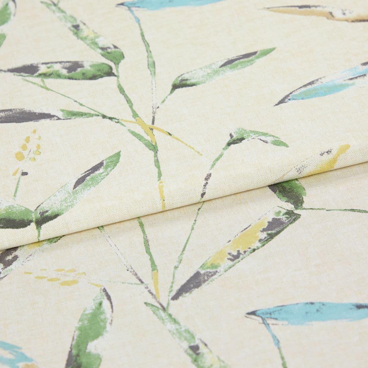 Linen-like curtain fabric, folded with a horizontal crease, printed with watercolor-style green, blue and yellow leaves; close-up studio shot on neutral beige background under soft light.